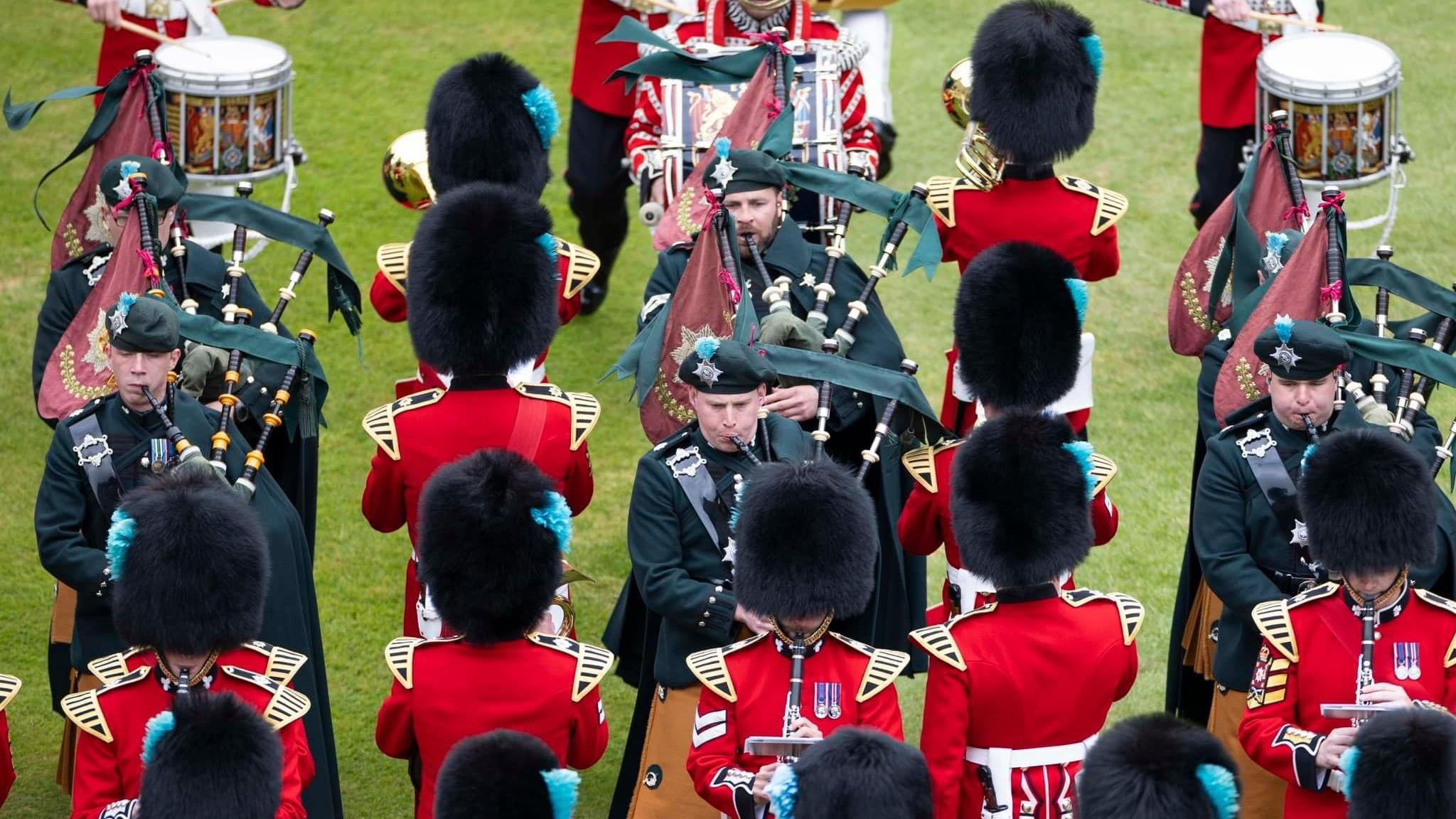 The Band and the Pipes of the Irish Guards on parade, showing people playing bagpipes and other musical instruments.