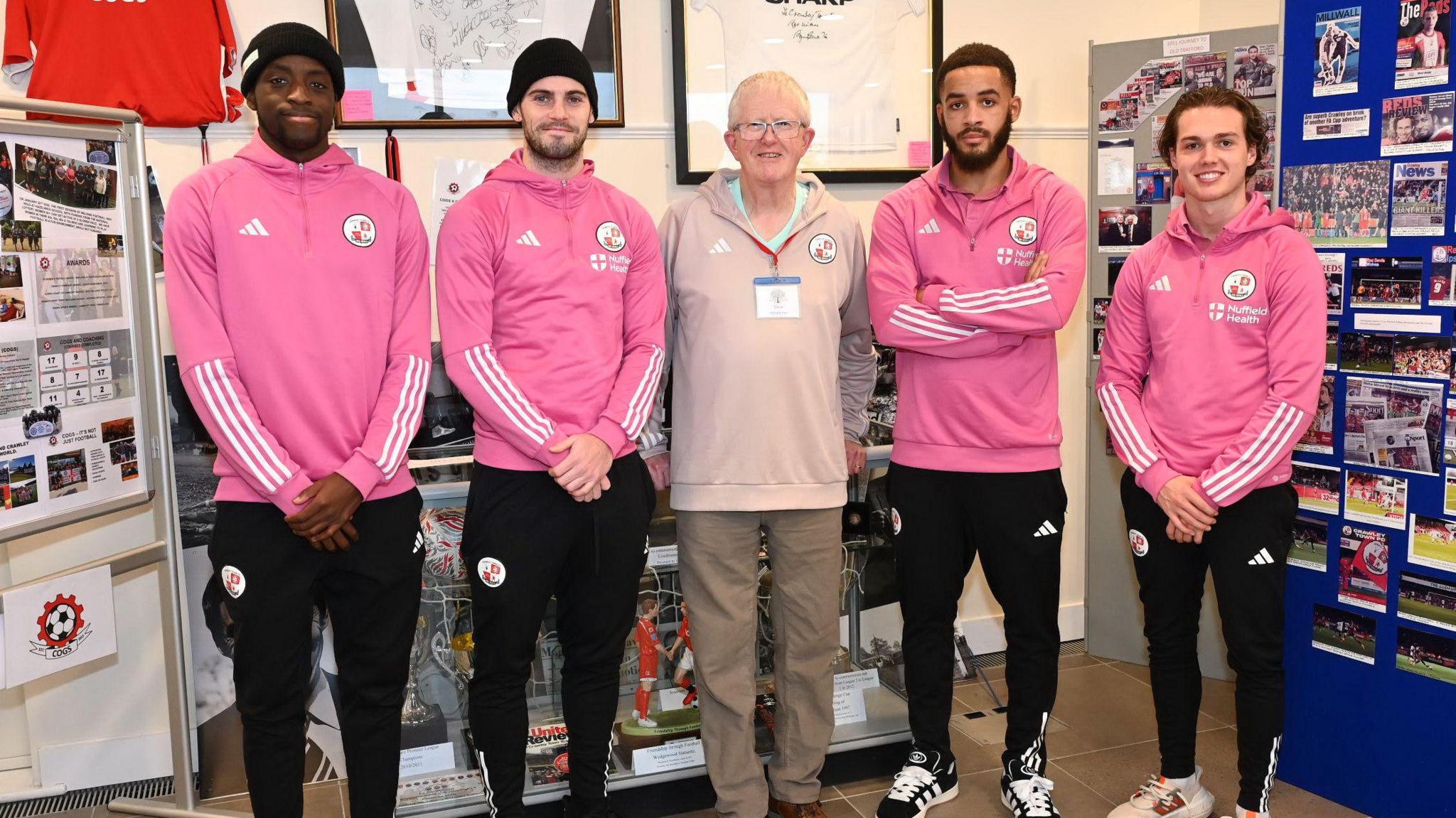 Steve Leake stands in the middle, with two Crawley players either side in the Crawley Town museum