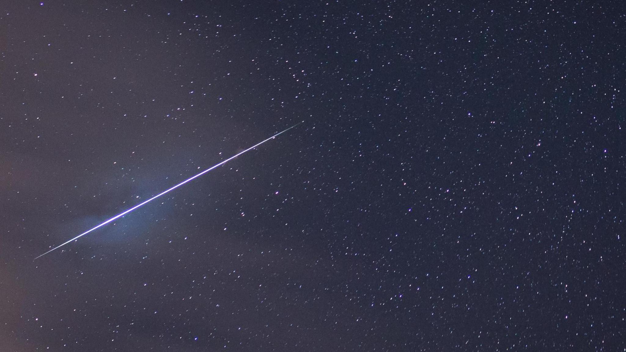 A blue shooting star blazes a trail across the night sky during the Geminid meteor shower