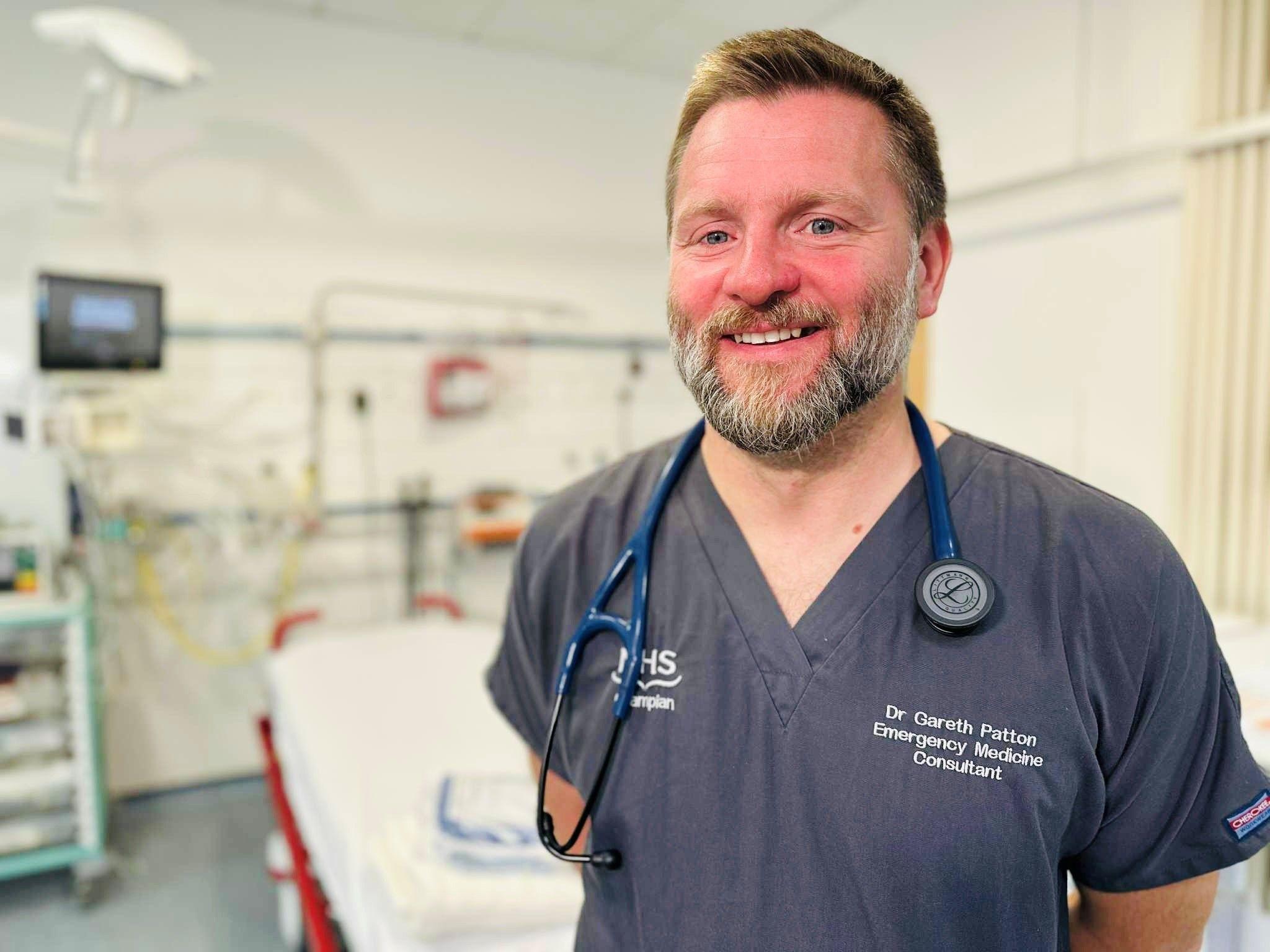 Gareth Patton, a doctor smiling at camera in a hospital room.