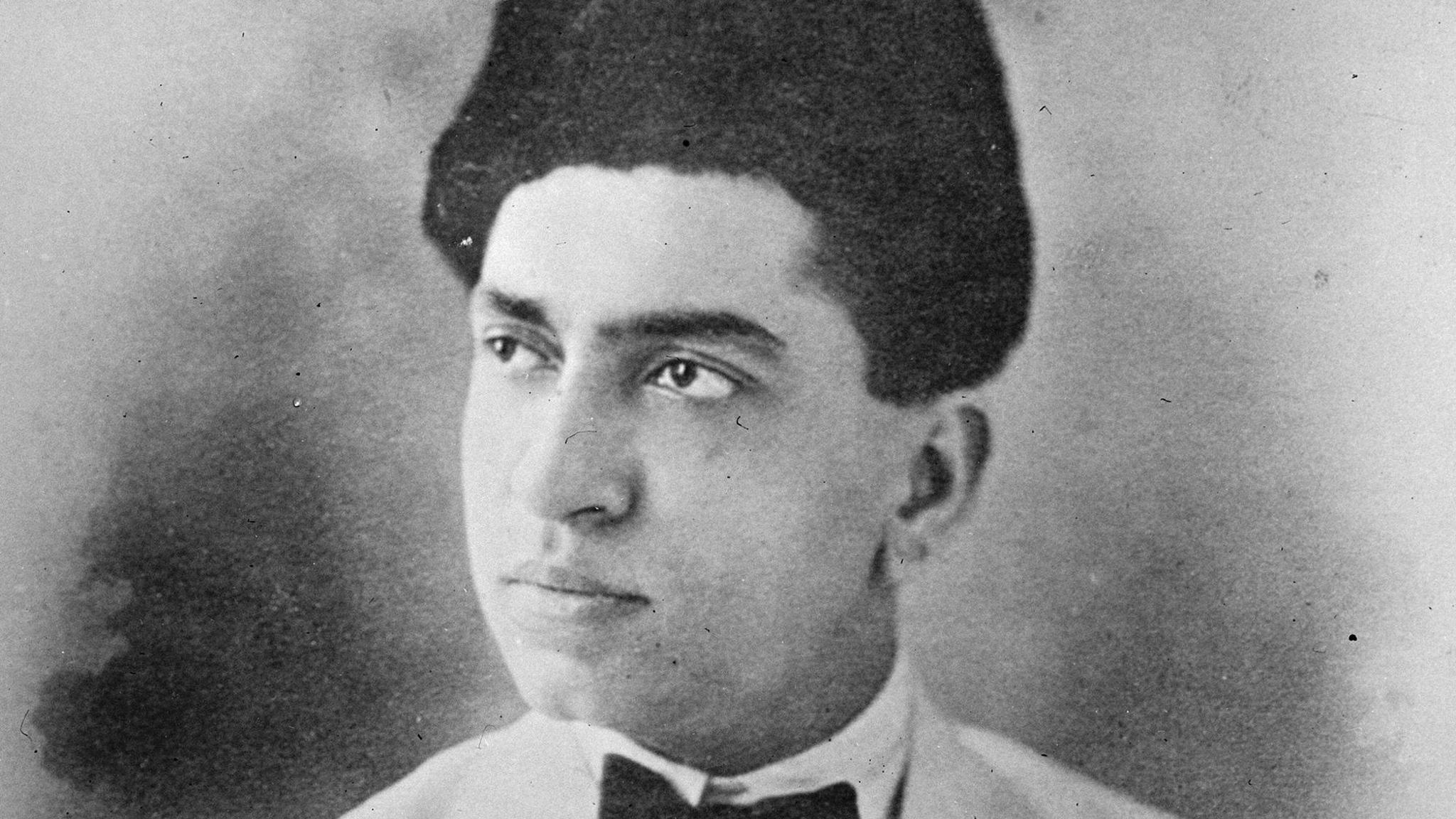 Abdul Kadir Bawla in a black-and-white photograph, wearing a suit with a bow tie and a traditional cap