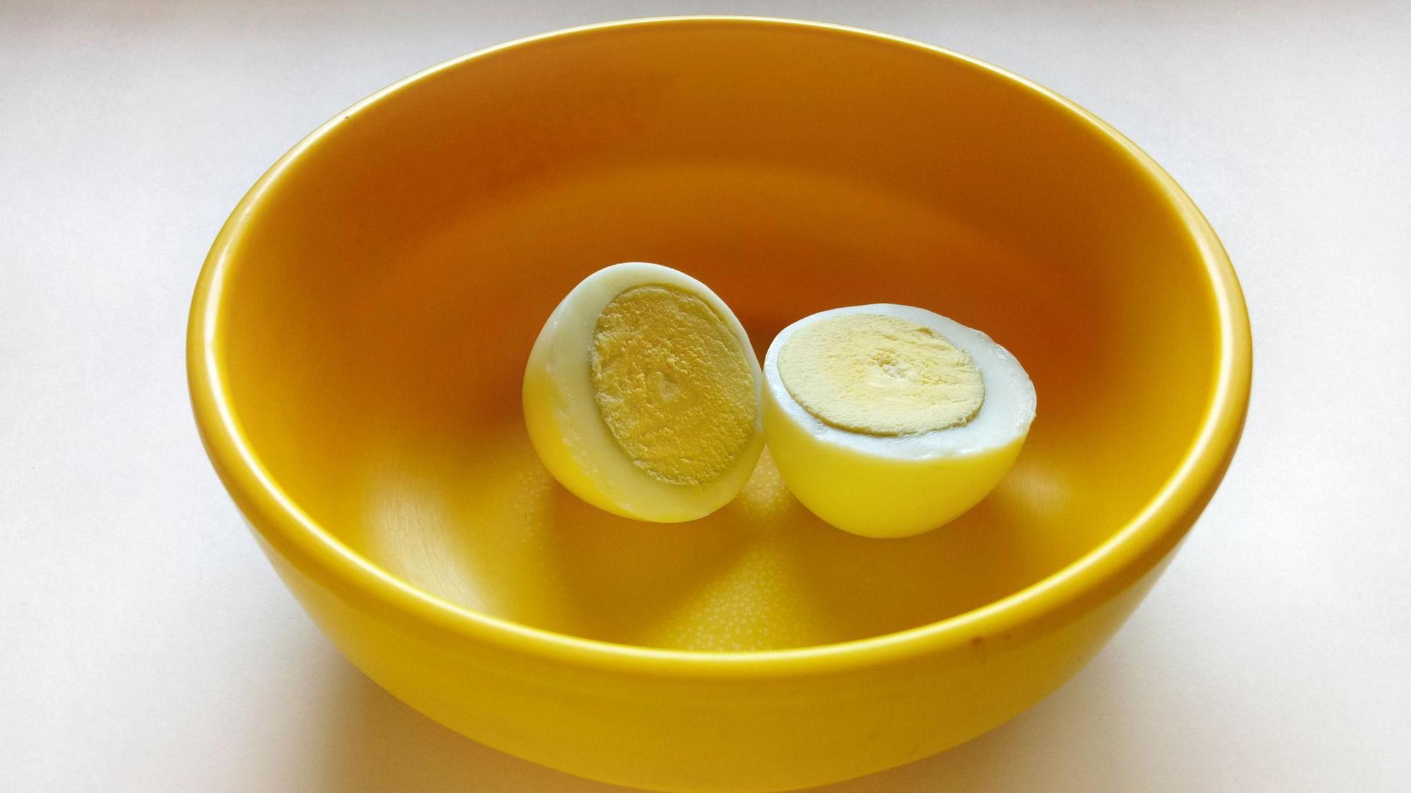 A boiled egg placed in a yellow plastic bowl 