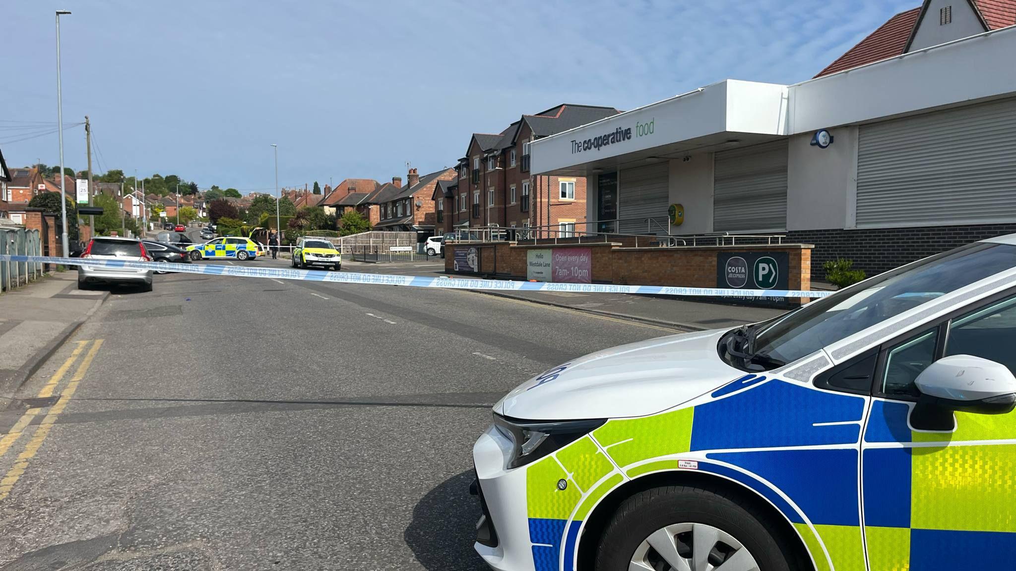 An image showing the front section of a police car in front of a police cordon outside the co-op in Gedling.