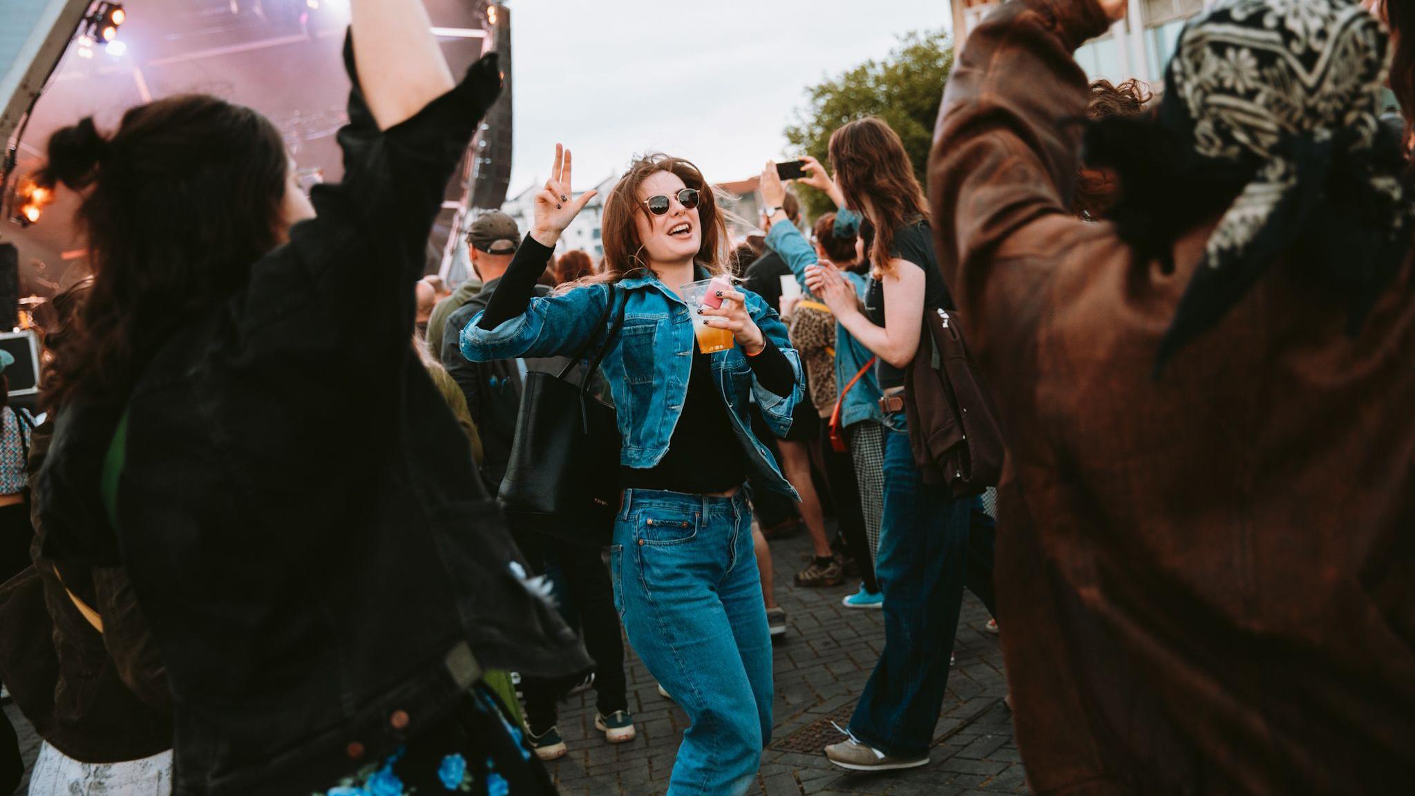 A woman is dancing and holding a drink in the audience