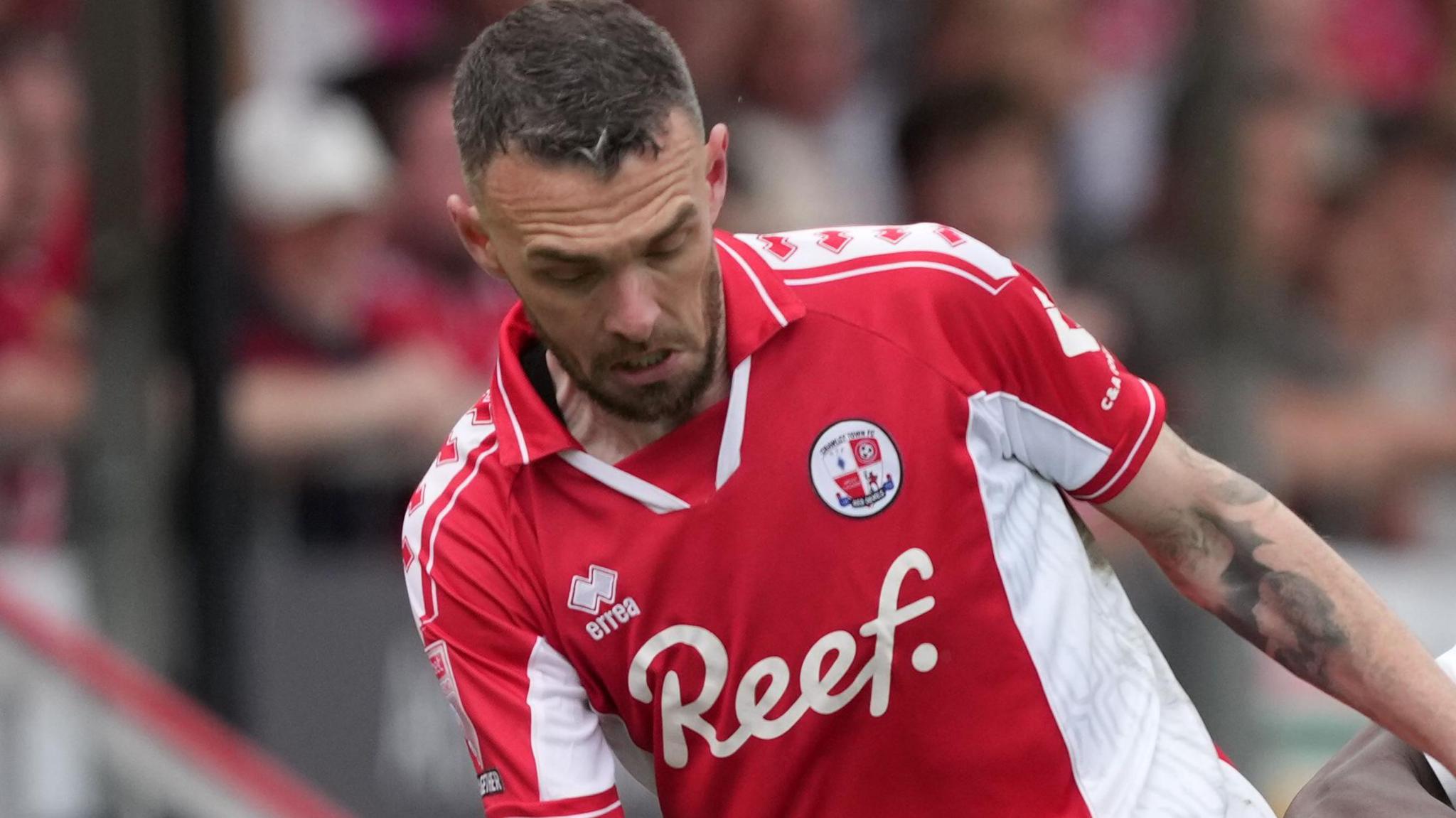 Scott Malone looks down towards the ball while playing for Crawley Town