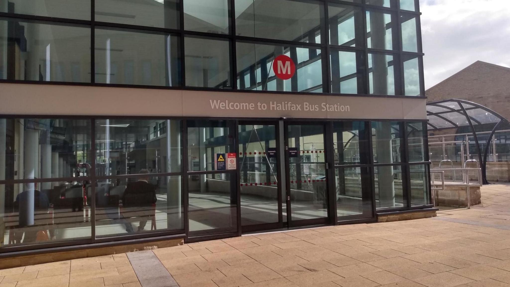 The new bus station is mostly glass and has a metro sign above its sliding glass doors.