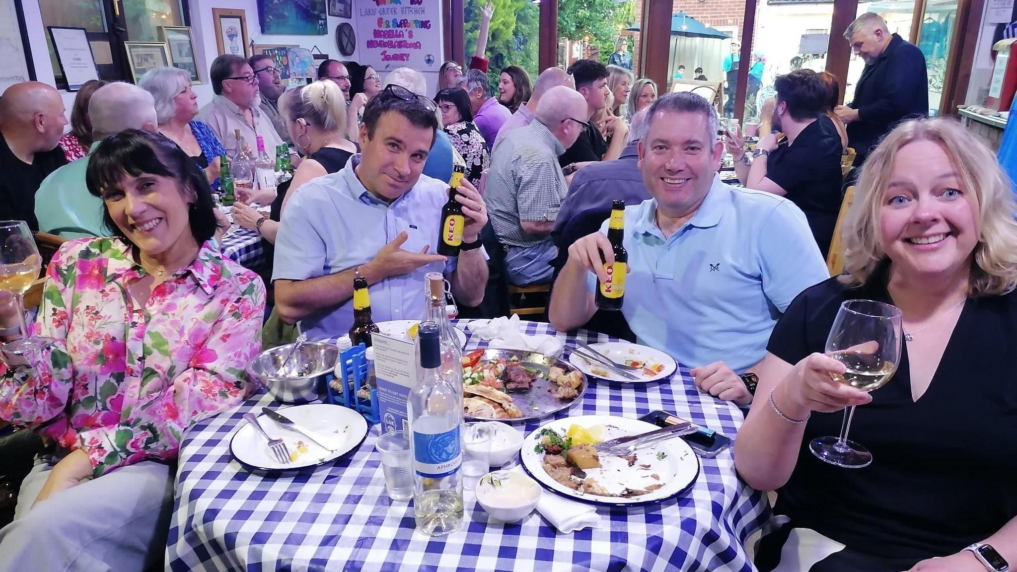 Four people sitting around a table in a restaurant, holding drinks