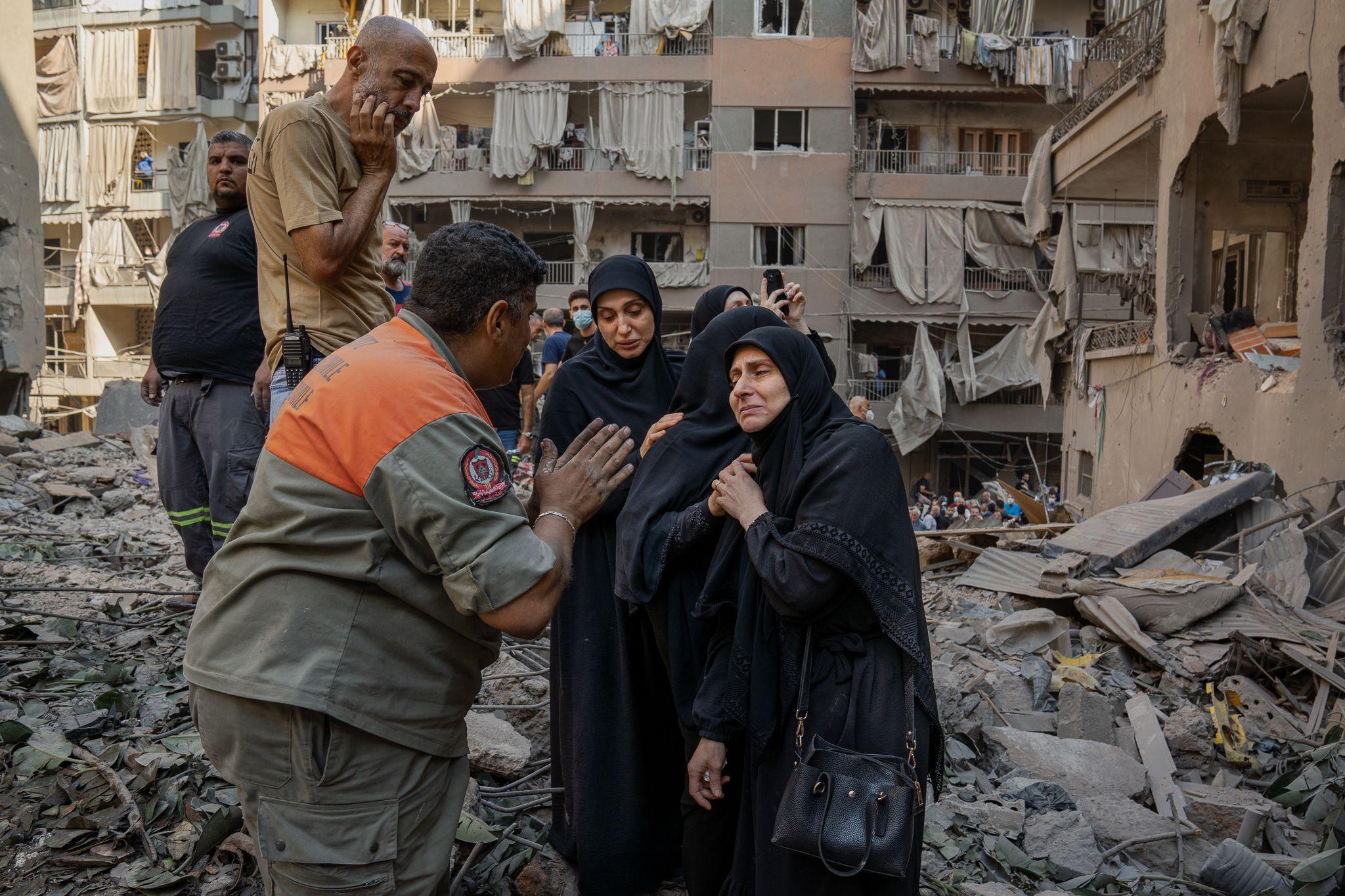 Distraught residents speak to Youssef Al-Mallah, the head of the rescue team, at the site of the Basta strike.