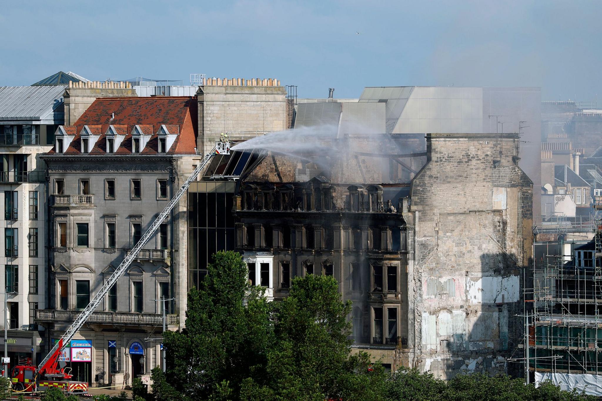 Firefighters dampen down a fire-damaged building
