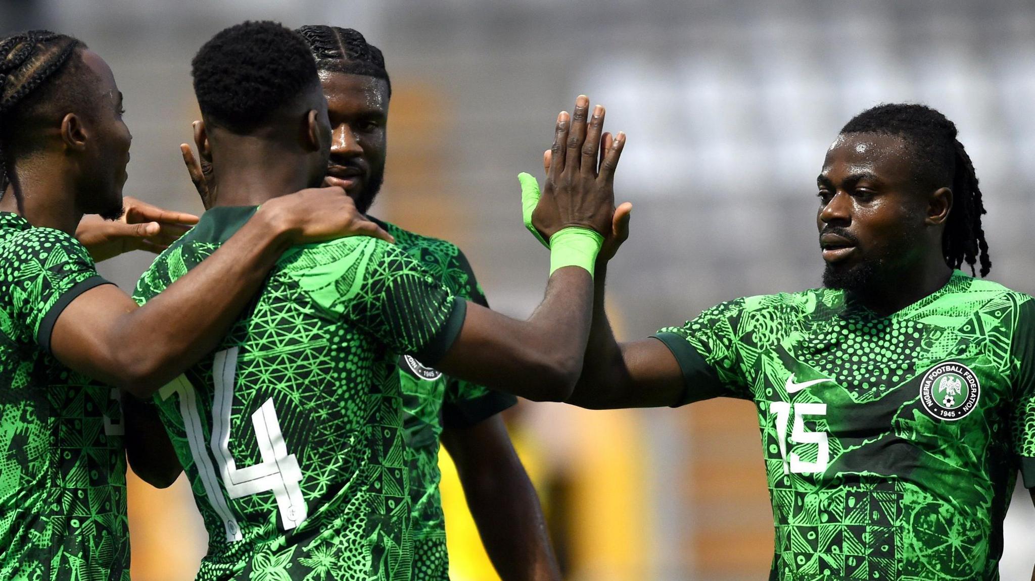 Moses Simon, wearing a green Nigeria jersey with the number 15 on it, is pictured giving a high five to team-mate Kelechi Iheanacho as the Super Eagles celebrate a goal