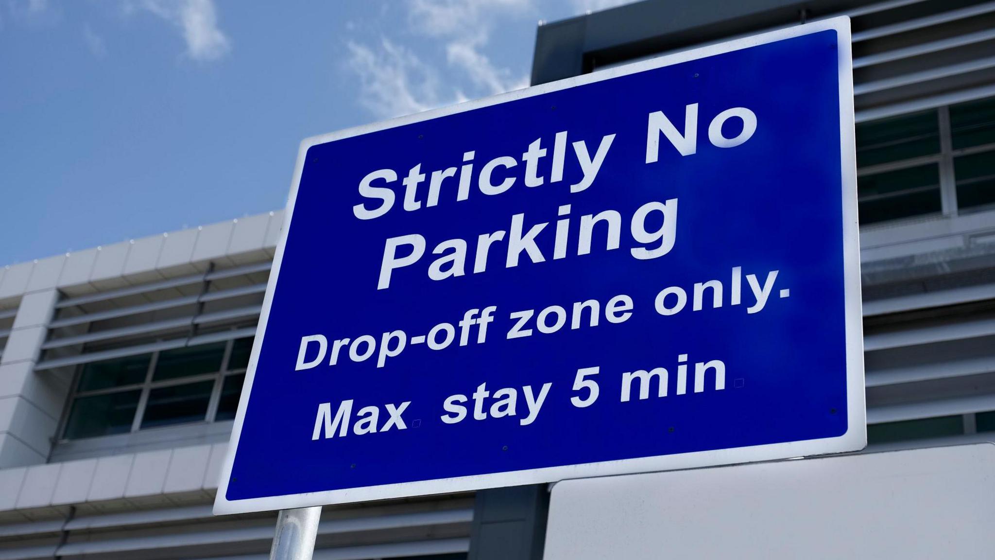 An airport sign saying "drop off only" on white letters on a blue background