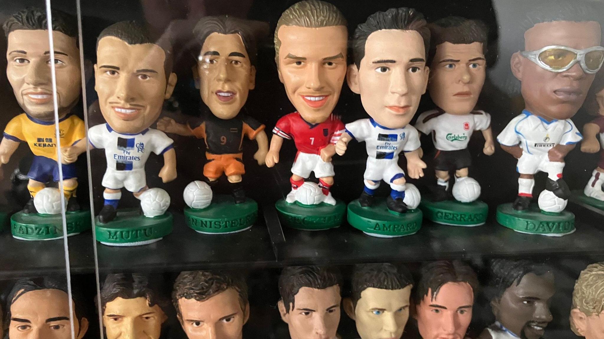 Two rows of Corinthian models behind a glass pane. The top row features some of England's squad, such as Frank Lampard and David Beckham.