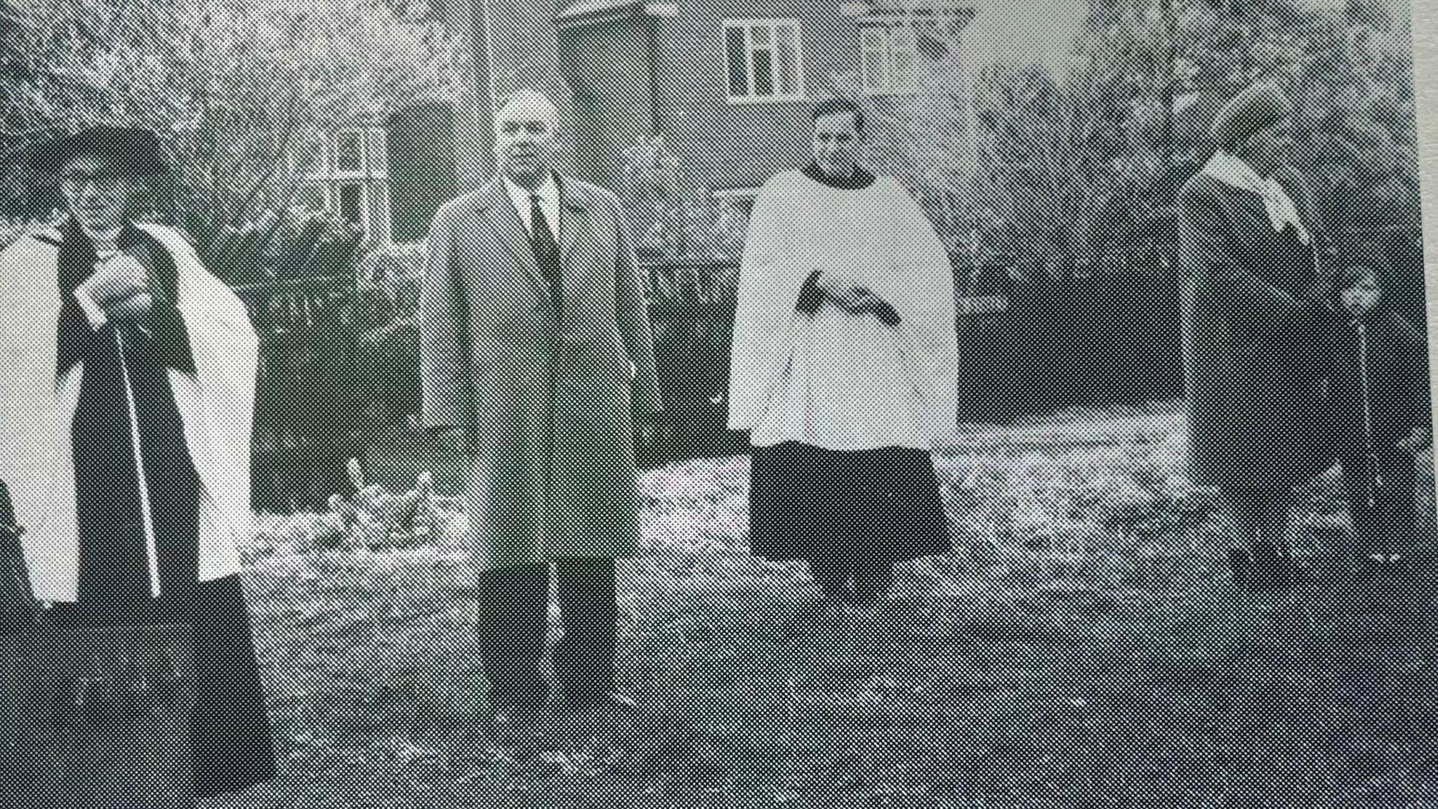 A black and white photograph of the men standing on the verge at the site where the tree is to be planted 