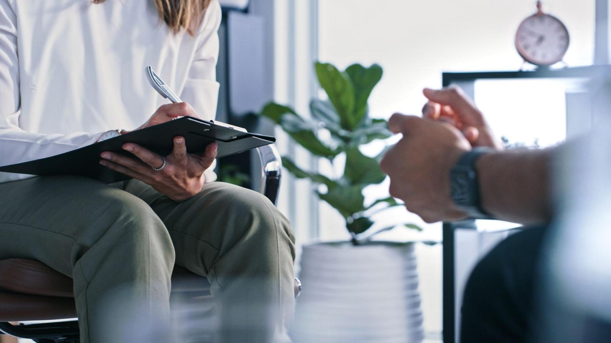 Closeup shot of shot of an unrecognizable female therapist writing notes while in session with a male patient