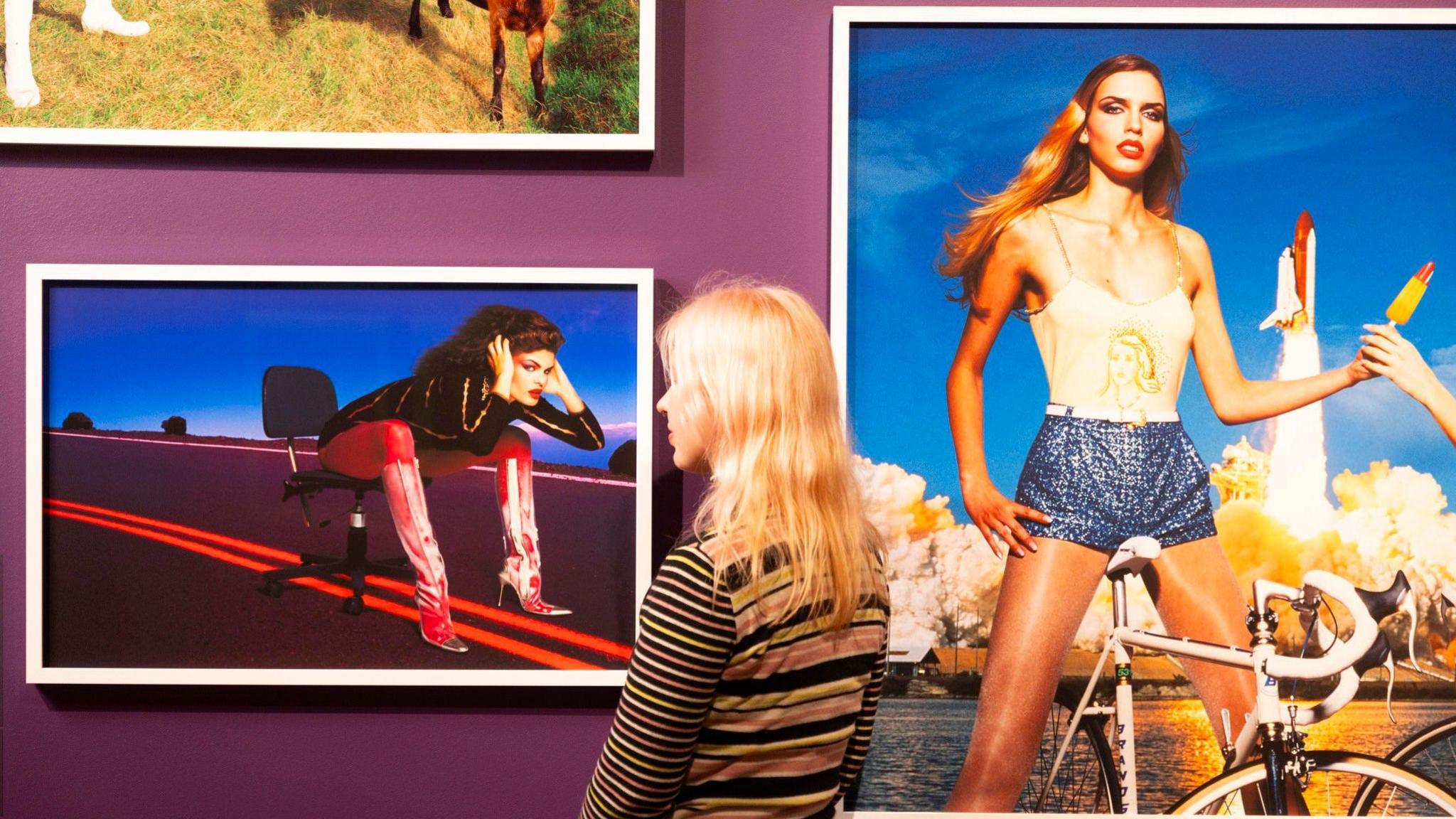 Blonde woman looks at portraits in the exhibition on the wall 