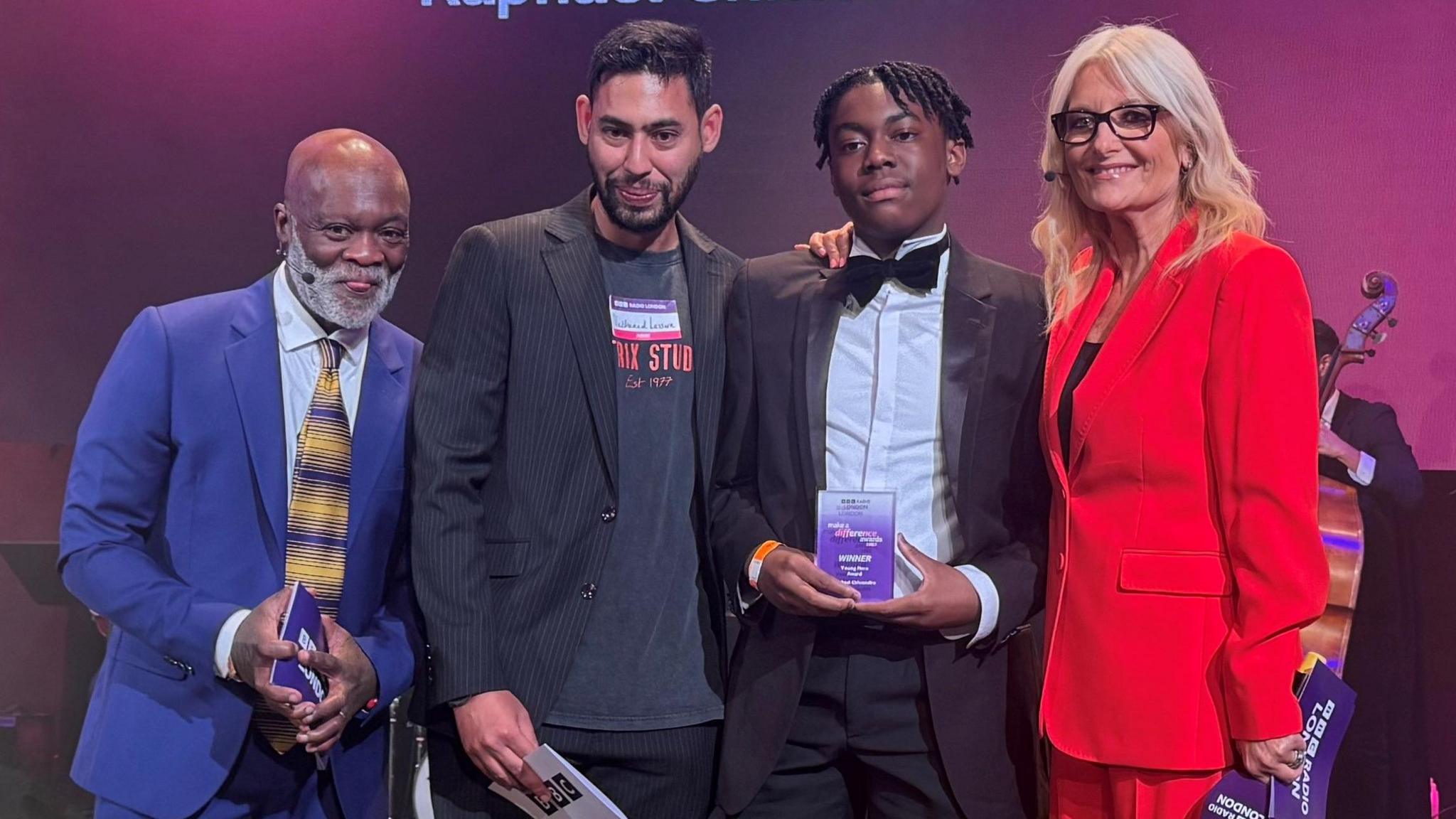 Raphael stands on stage with his award and the hosts