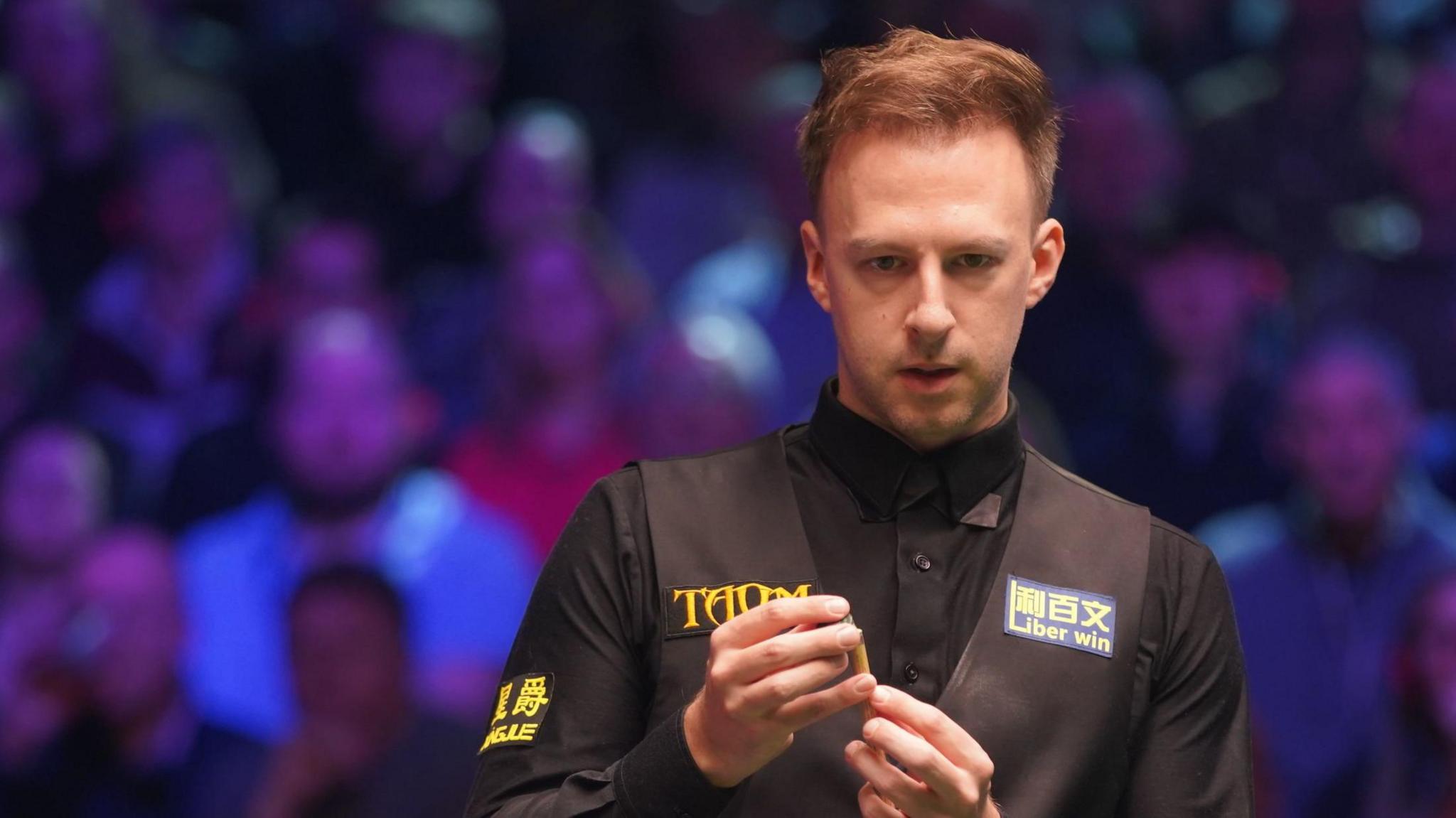 Judd Trump chalking his cue