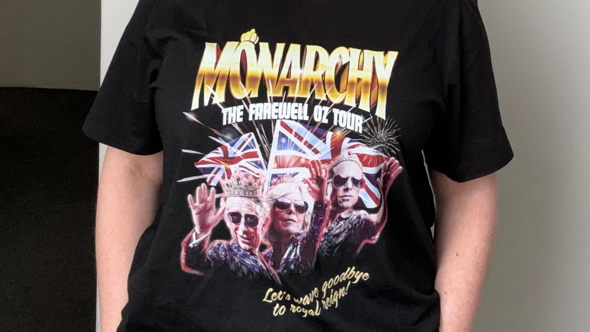 A woman wearing the Australian Republican Movement merch. It's a t-shirt which reads "Monarchy the farewell Oz tour" and "Let's wave goodbye to Royal reign!". It features edited photos of King Charles in a crown, Queen Camilla and Prince William. All three are wearing sunglasses.