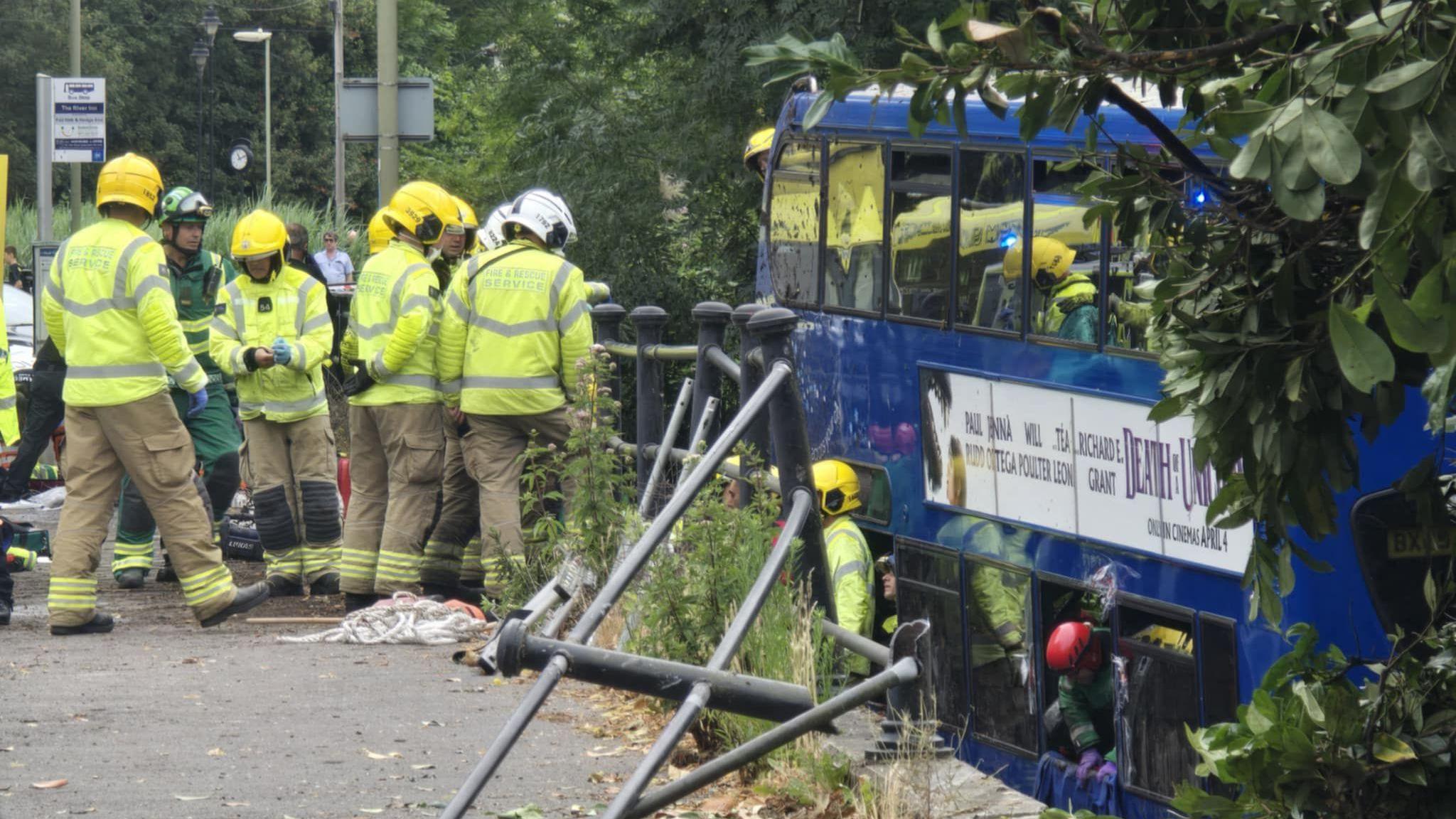 Emergency services near a bus with broken railings in the foreground