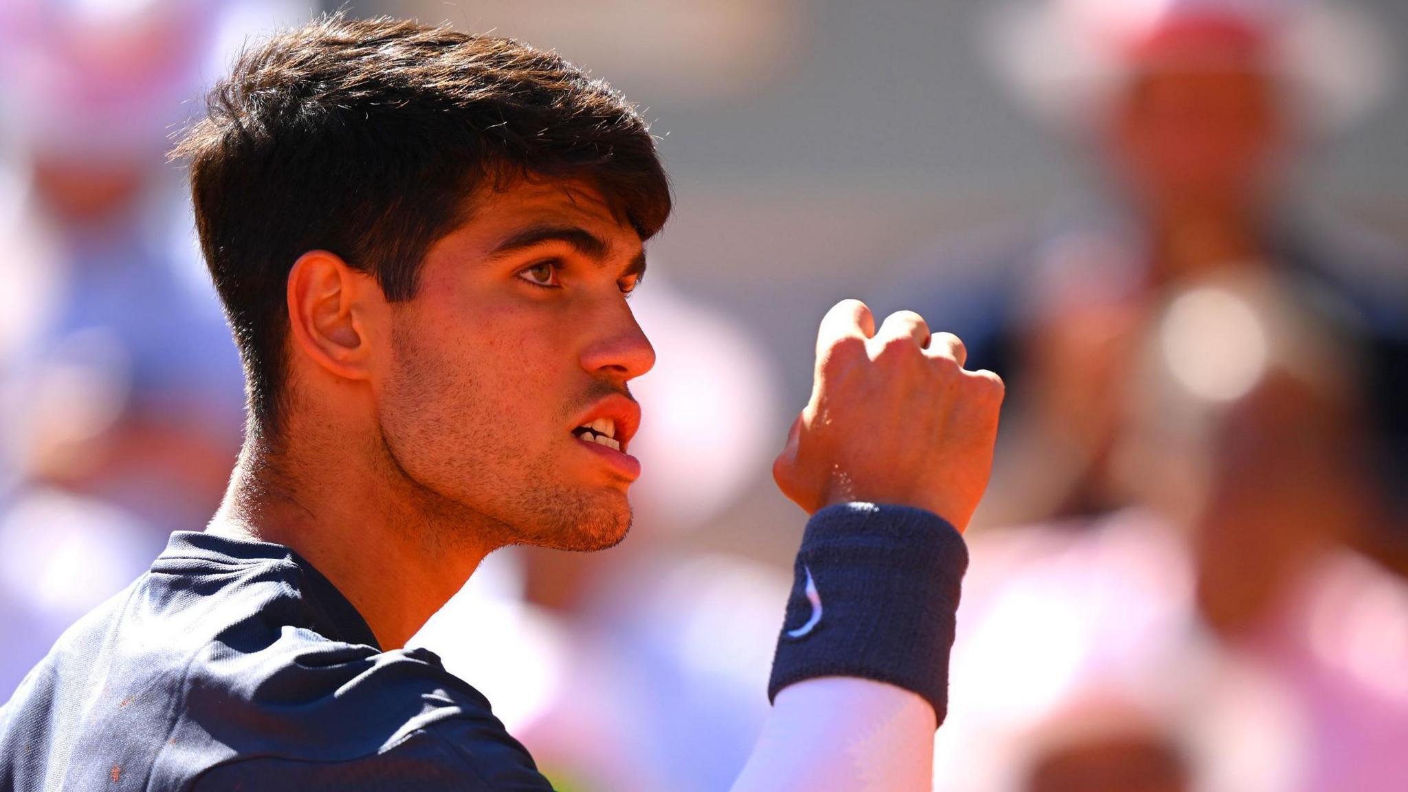 Carlos Alcaraz clenches his fist and his teeth in celebration at the French Open