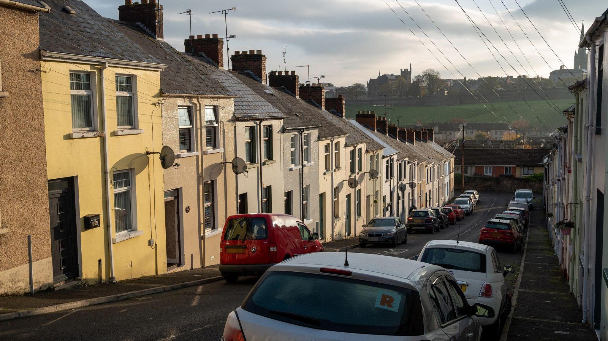 Limewood Street in Derry's bogside, seen from the top of the street looking down at cars parked on either side of the road, and rows of terraced houses on both sides