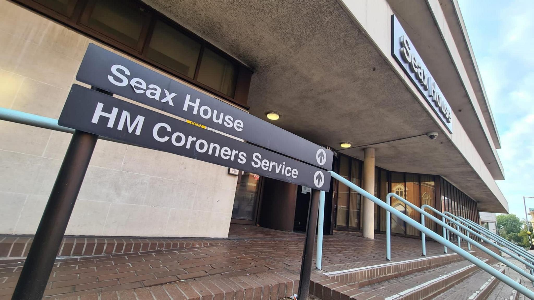 The front of Seax House in Chelmsford, showing signage, steps and railings, brick paving and concrete overhanging floors.