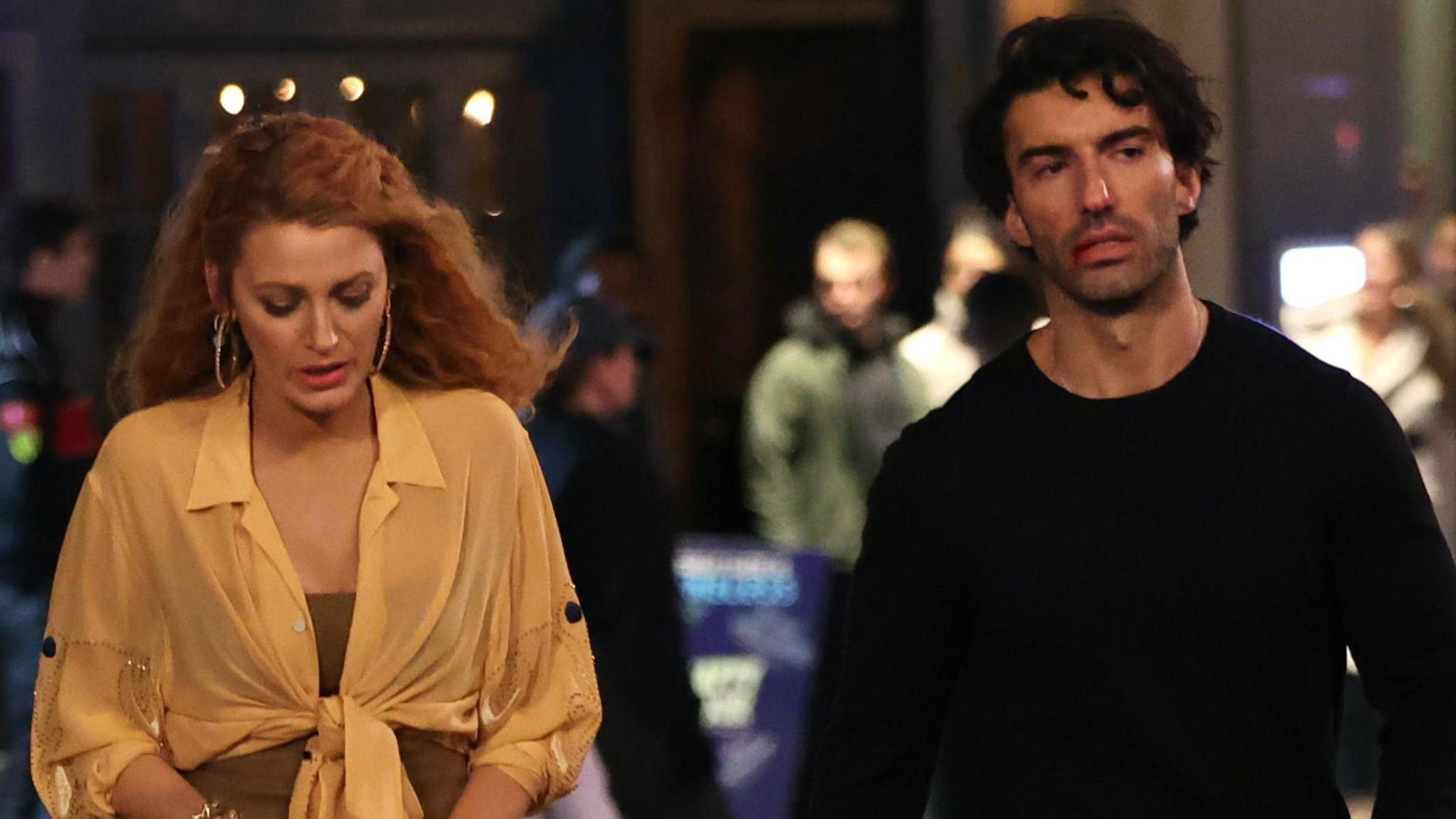 Blake Lively, wearing a yellow shift, alongside Justin Baldoni, wearing a black jumper, on the set of The Last of Us in January 2024
