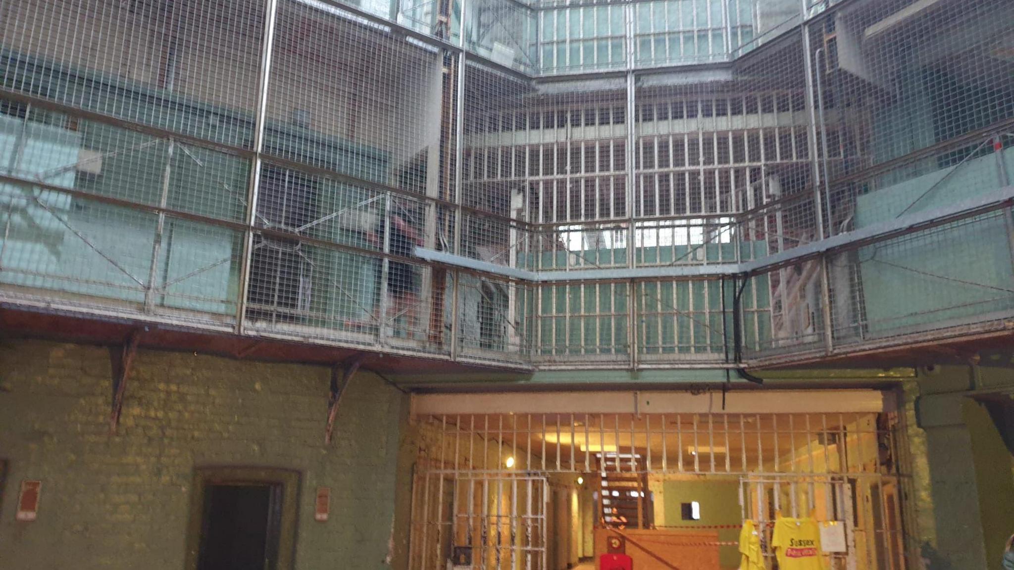 The inside of Dorchester Prison. It is three tiers with metal grating covering each balcony tier.