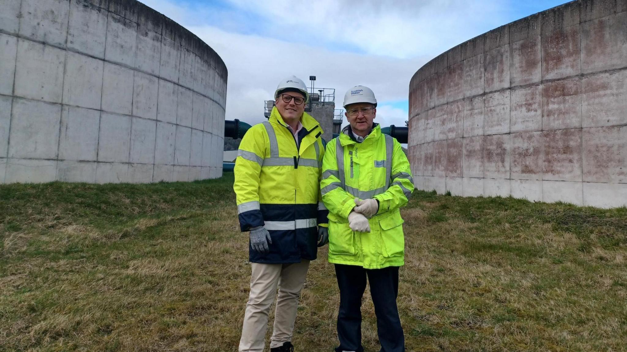 Two men standing between silos at Inverness's waste water pumping station on Longman drive