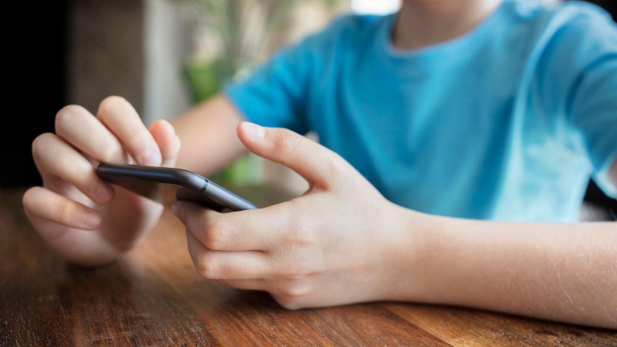 Boy scrolls on his mobile phone. Close up on the phone and his hands