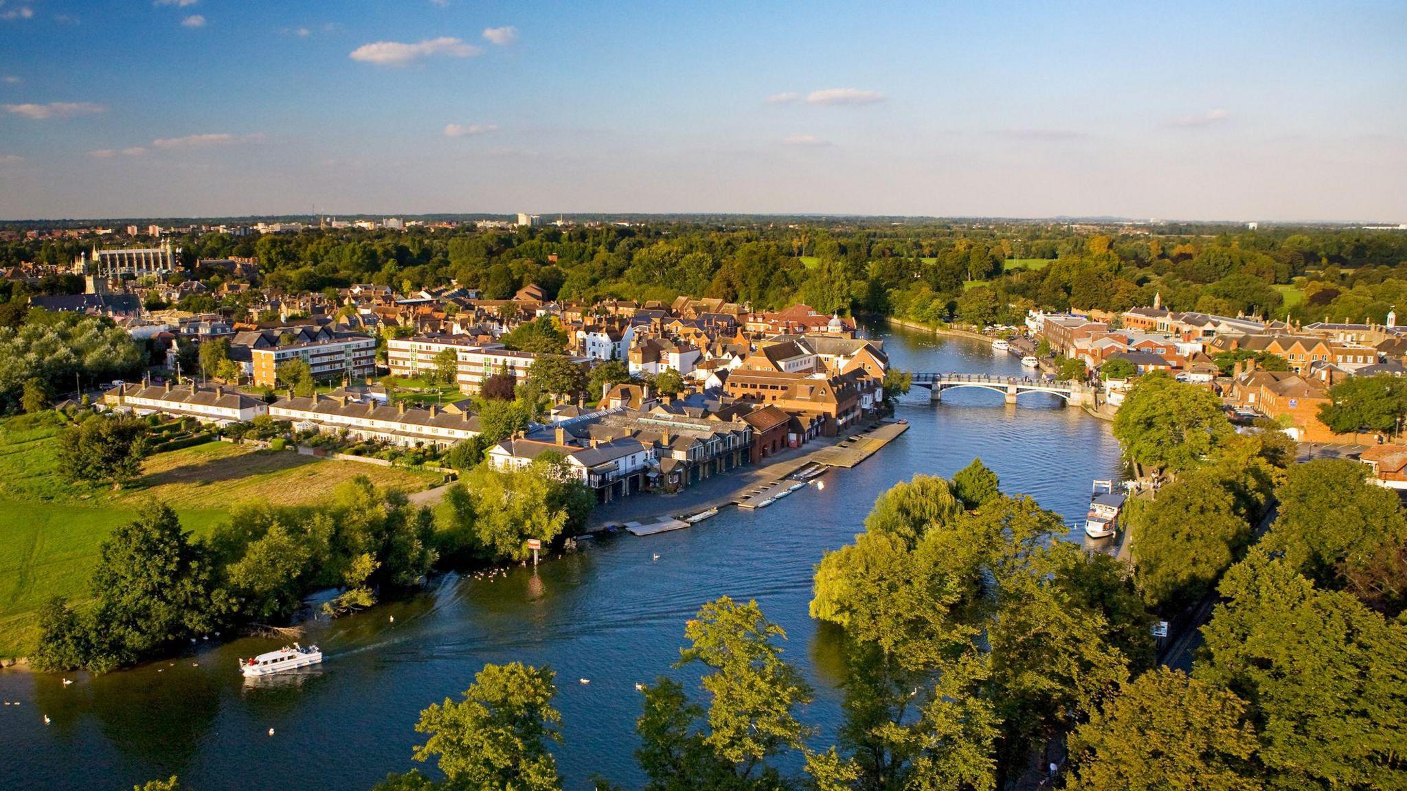 An aerial photo of a river with a bridge going across it and buildings on either side.