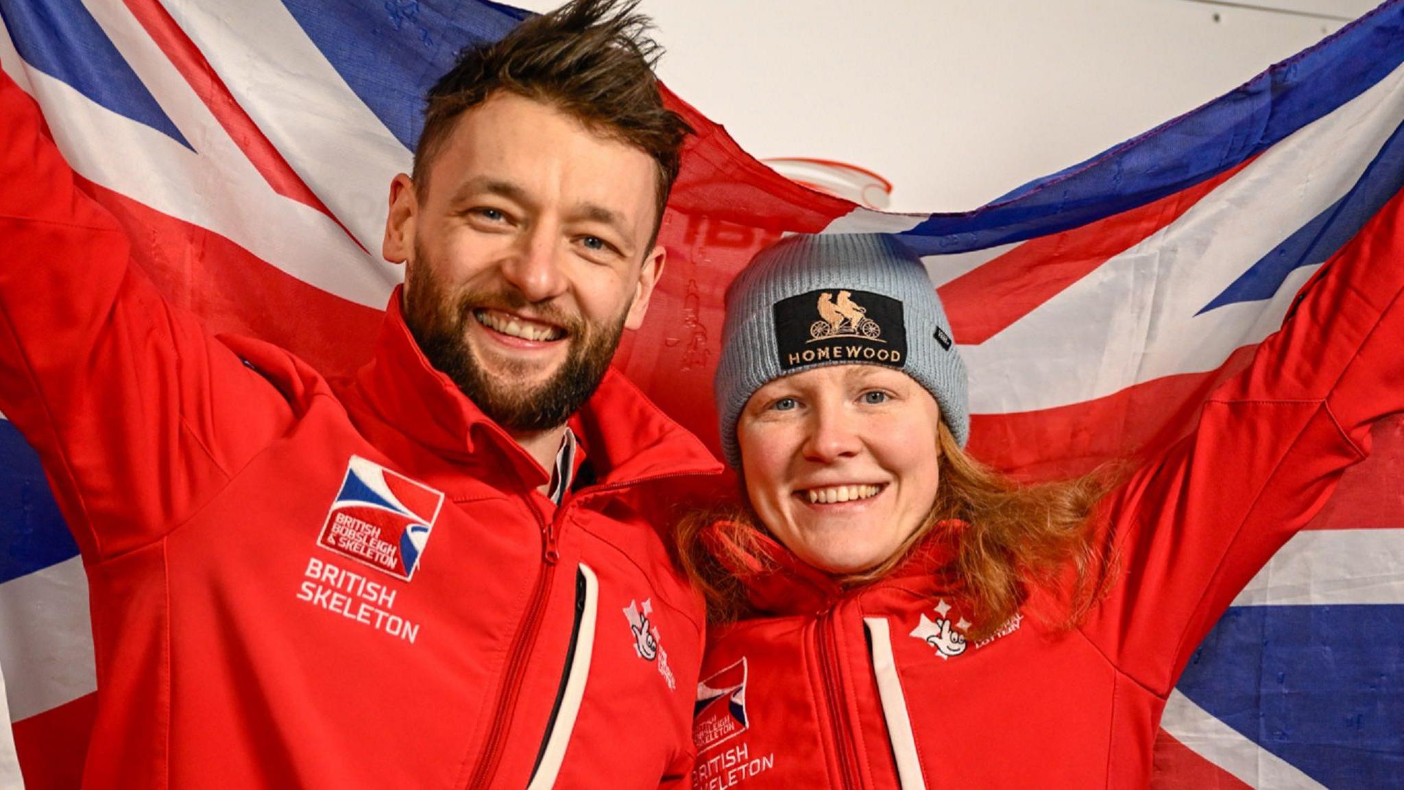 Marcus Wyatt and Amelia Coltman smile while holding a British flag