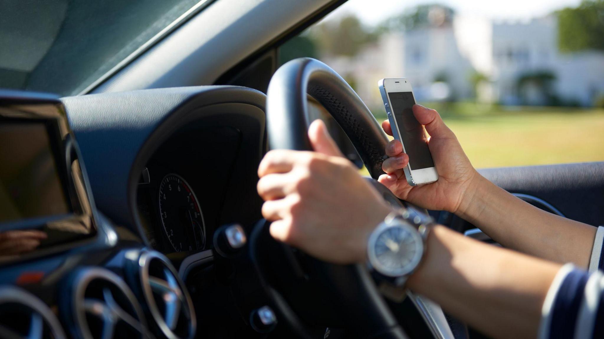 Young woman texting while driving