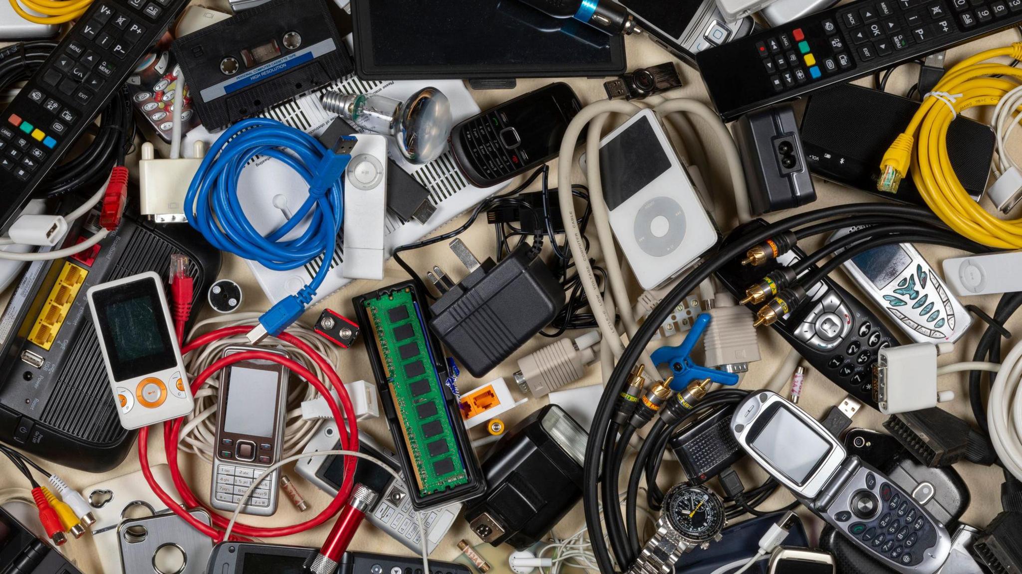 A large pile of old electronic good likes phones and wires