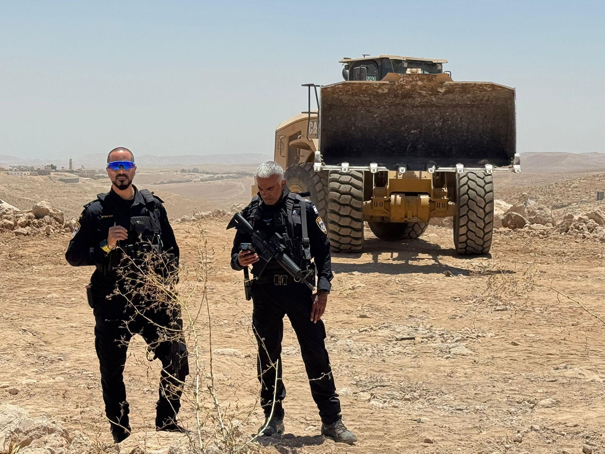 Police guard a digger extending the settlement of Carmel near Umm al-Khair, in the southern West Bank
