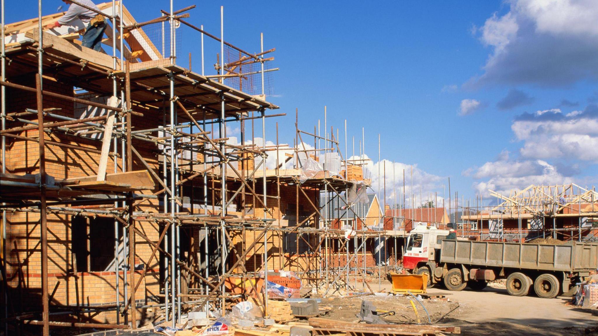 A construction site, with workers building four-bedroom houses