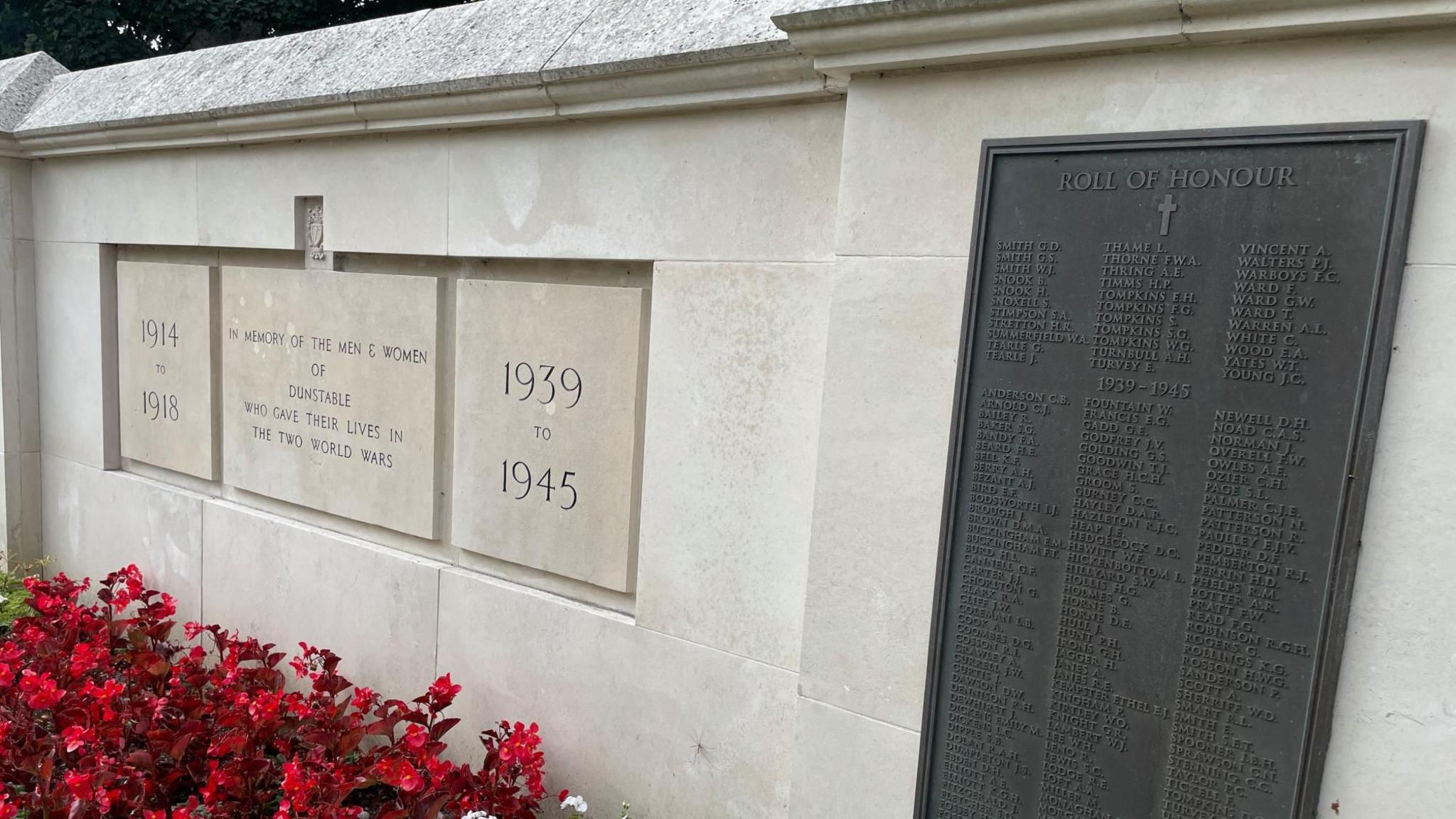 Dunstable War memorial. A white stone structure with the dates of both world wards inscribed on it. A roll of honour is visible with many names.