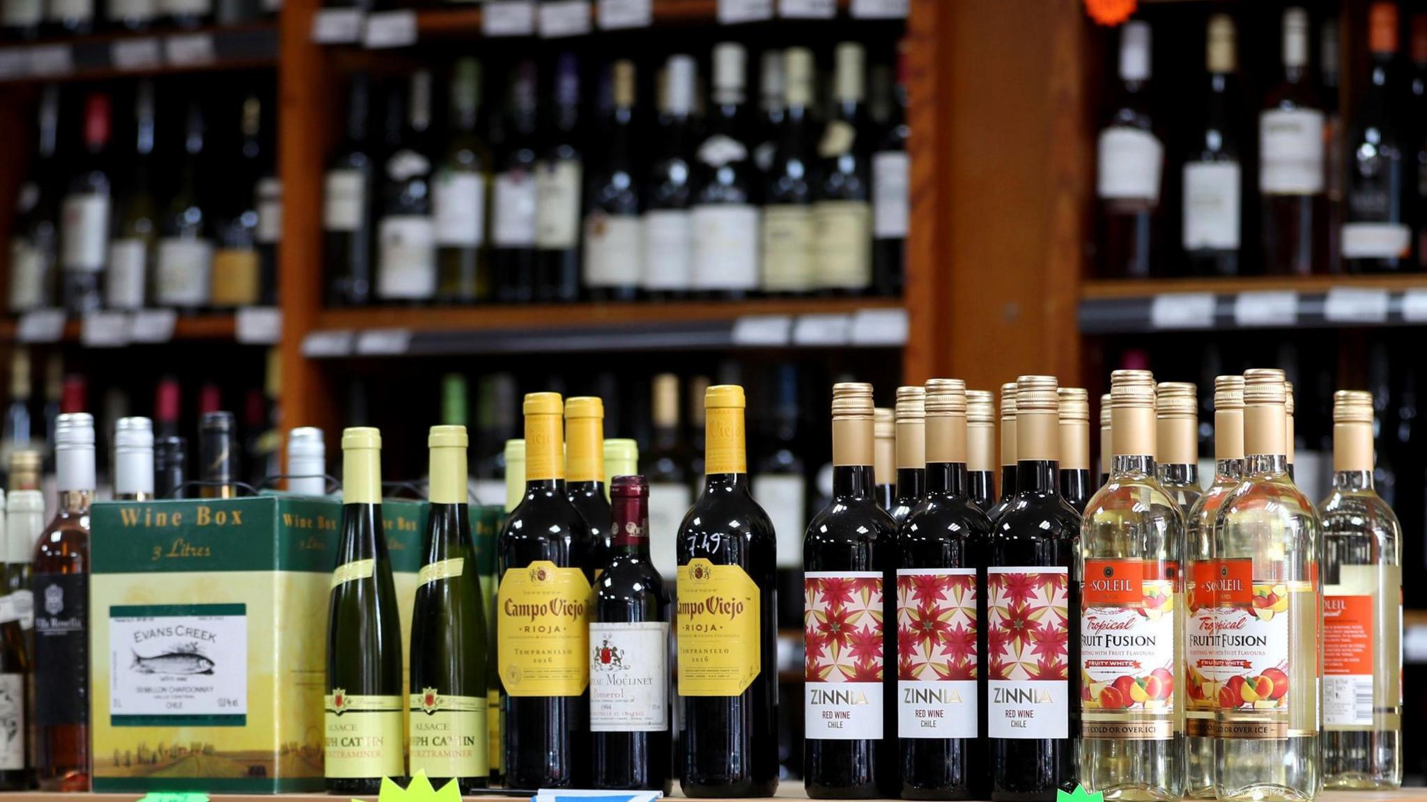 A wine shop with bottles of wine on a shelf and more shelves of wine in the background