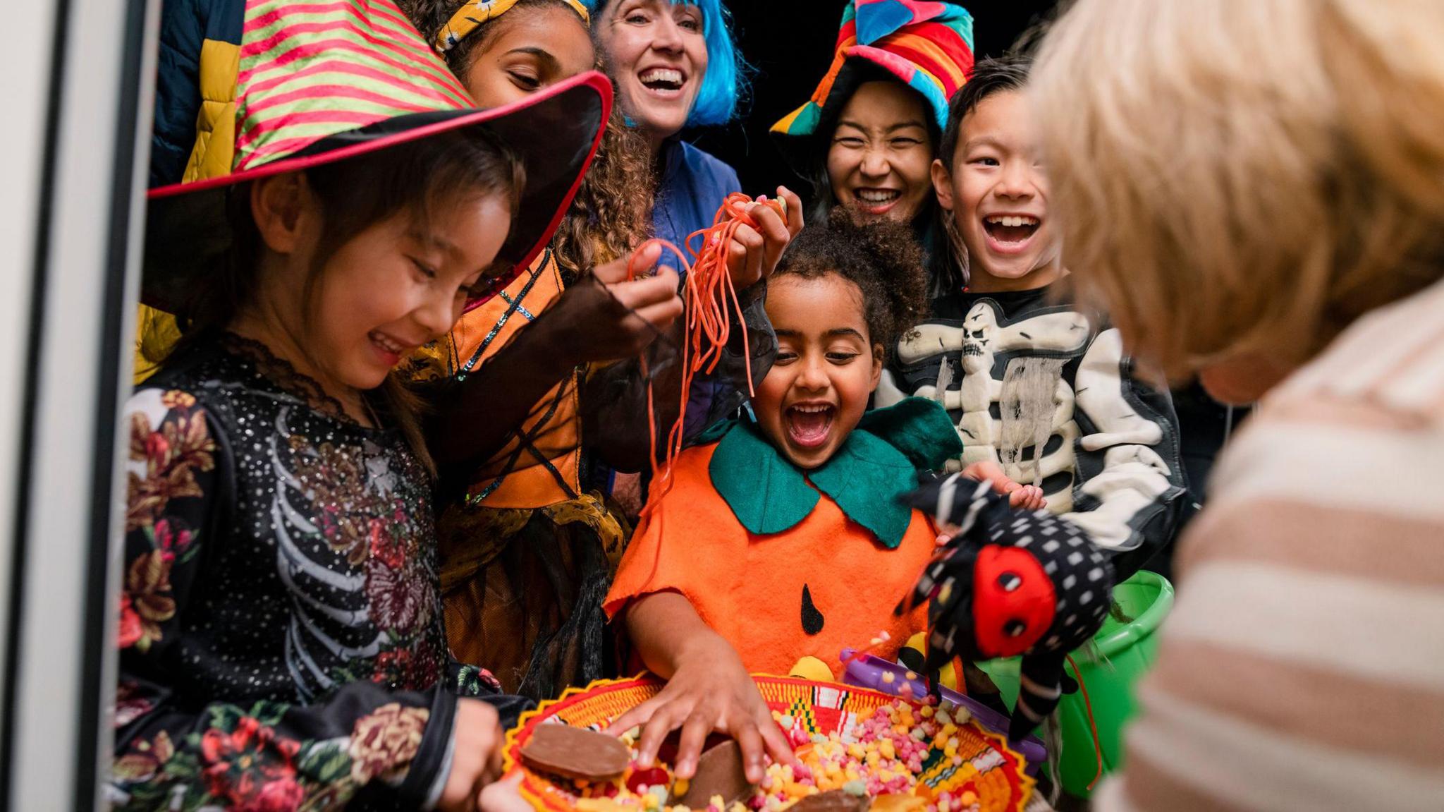 a group of kids and their parents dressed up for halloween trick or treating at someone's door