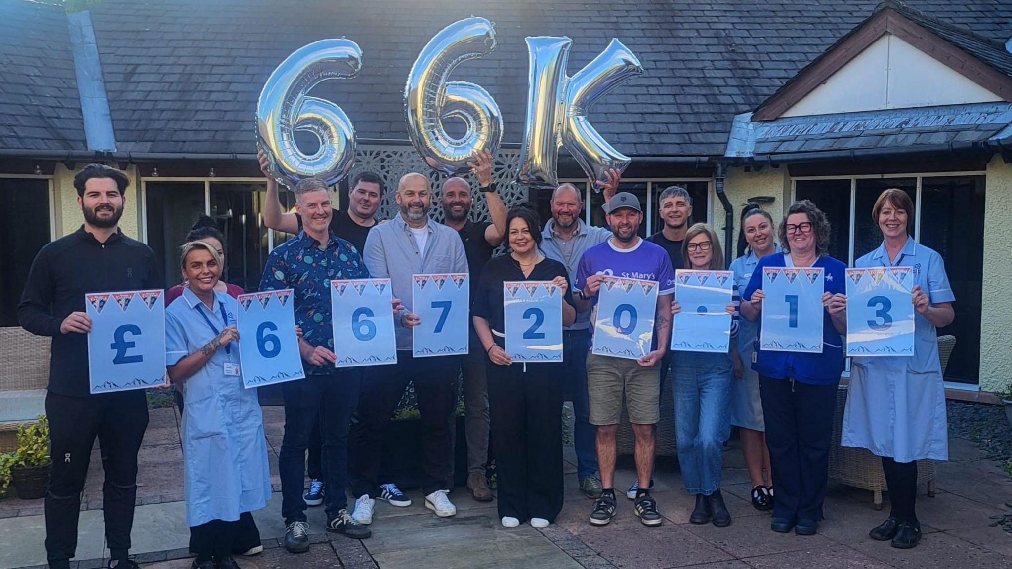 The group holding balloons and signs celebrating the amount raised