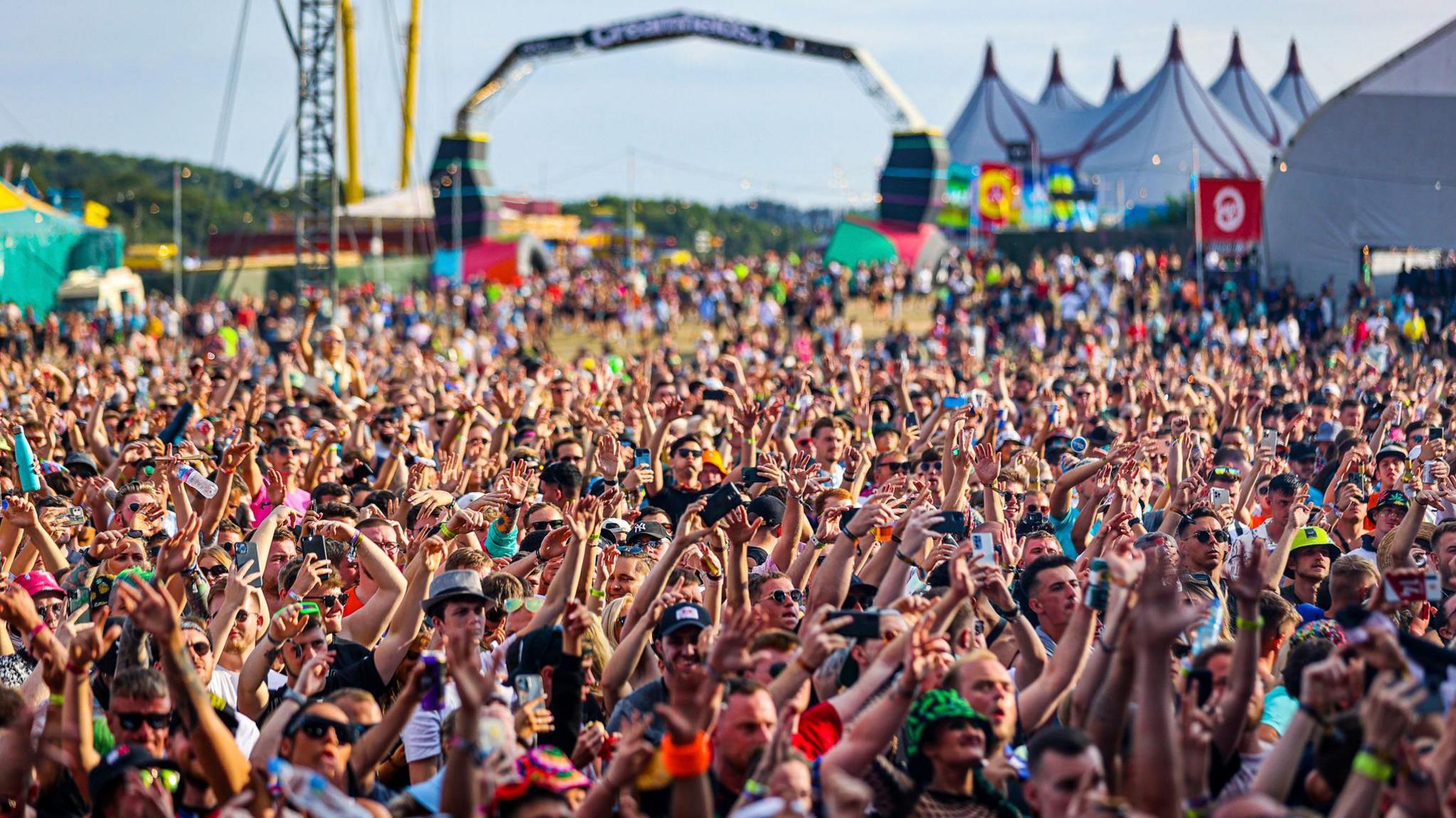 Crowd at Creamfields festival in the sun raising their arms