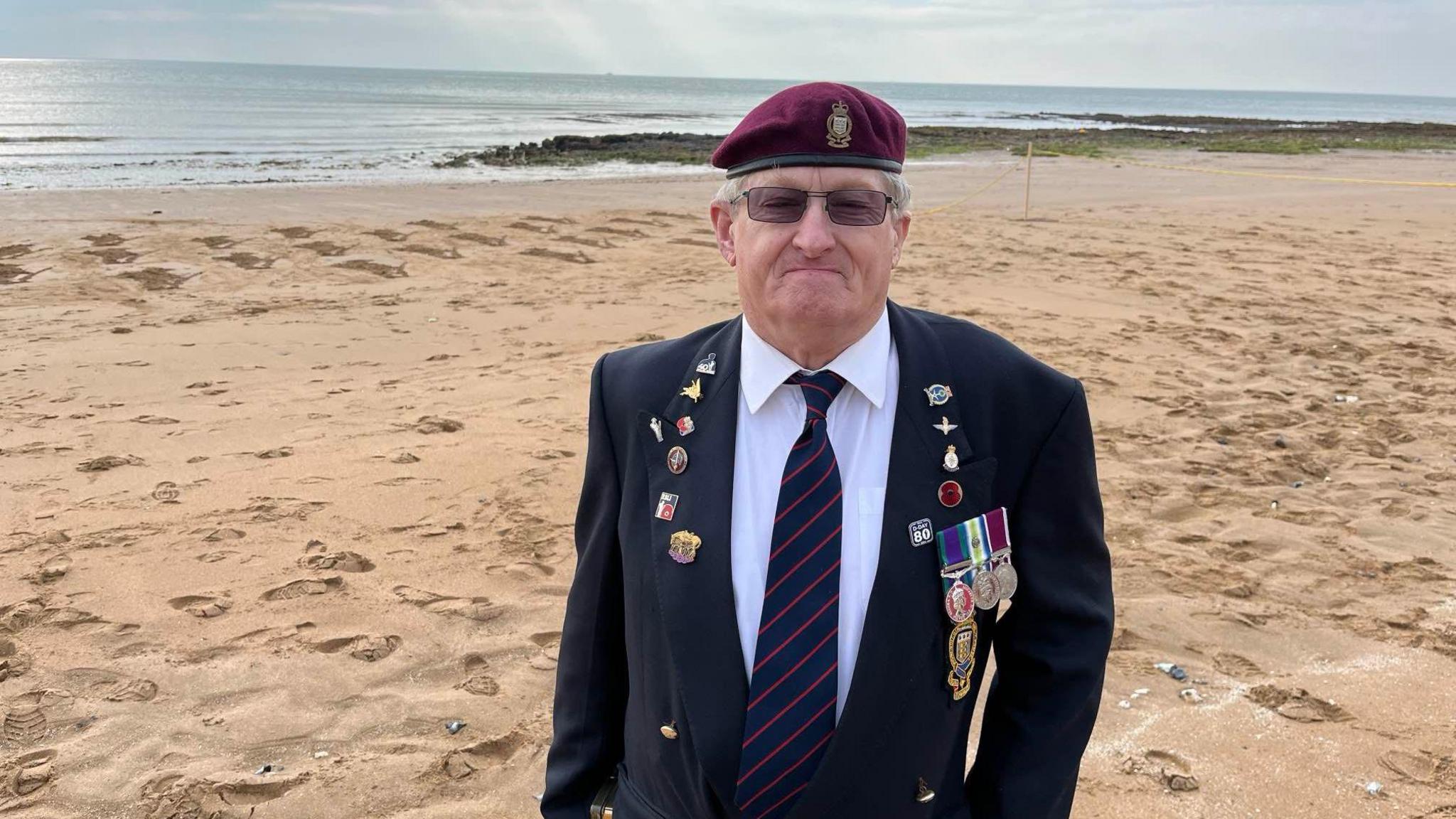 Veteran Pete Gower standing in front of the installation on the beach 