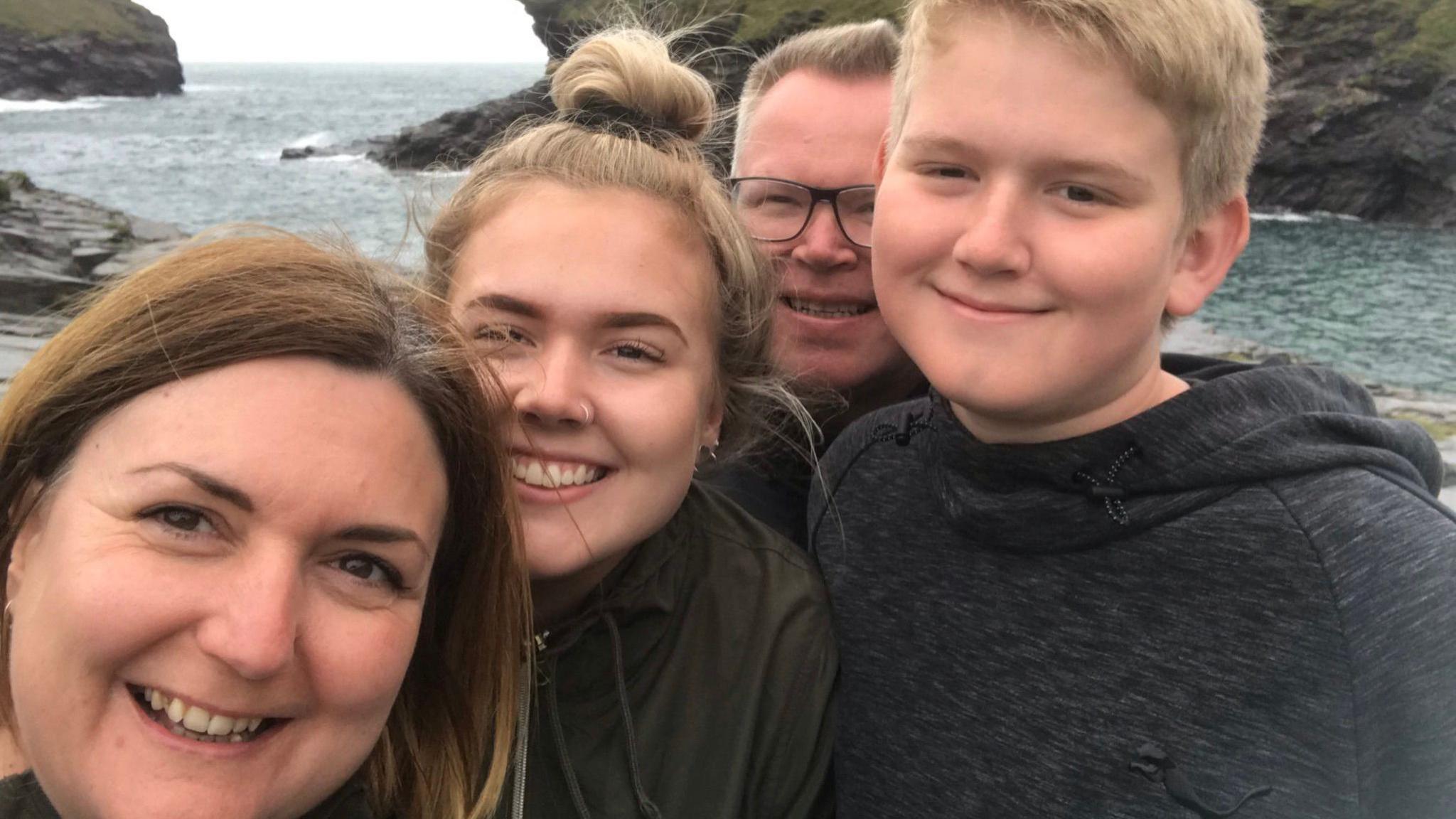 Family picture of the Priestley family with sea and cliffs behind them.