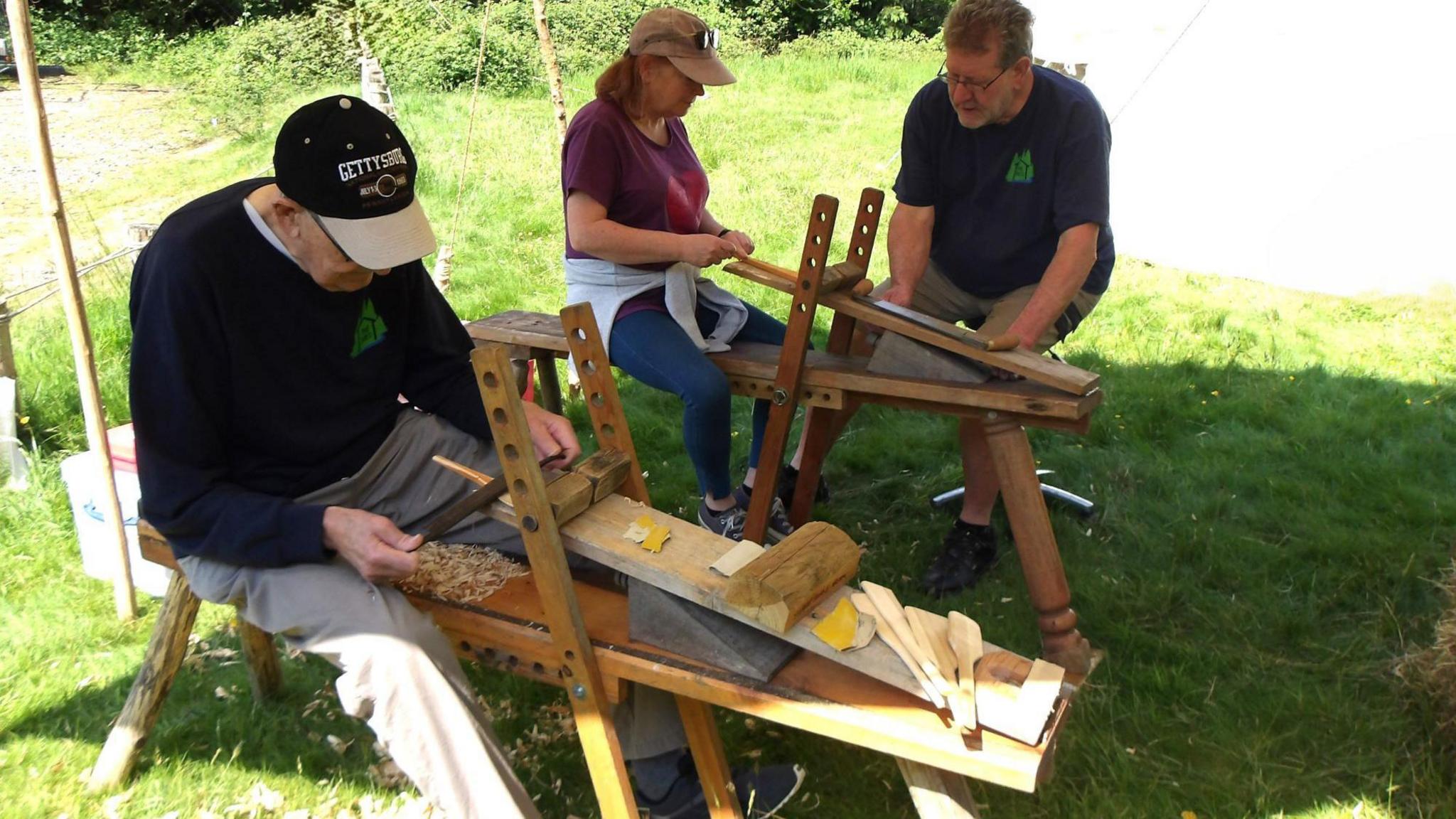 Two people working with wood outside