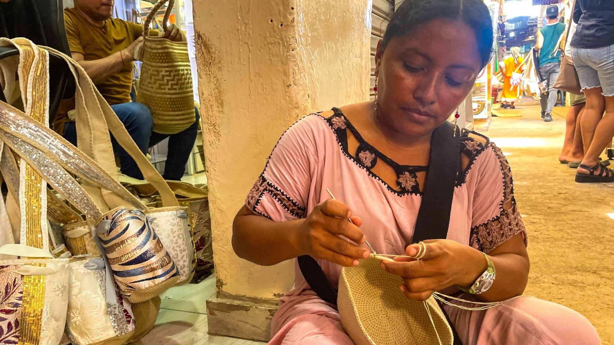 A weaver working as she sits on the floor in the Mercado Nuevo market