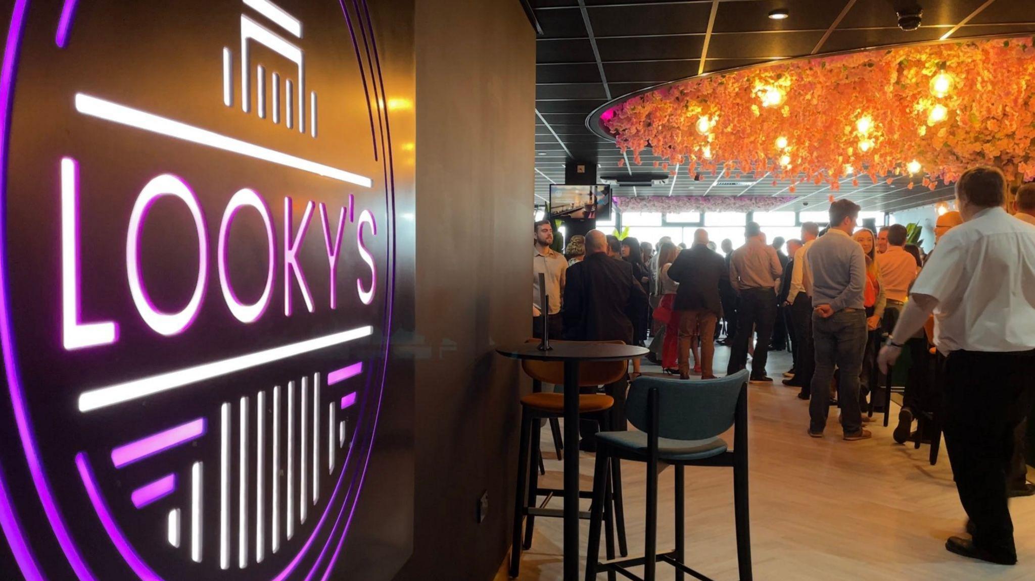 View of people standing in a lounge bar with an illuminated sign in the foreground