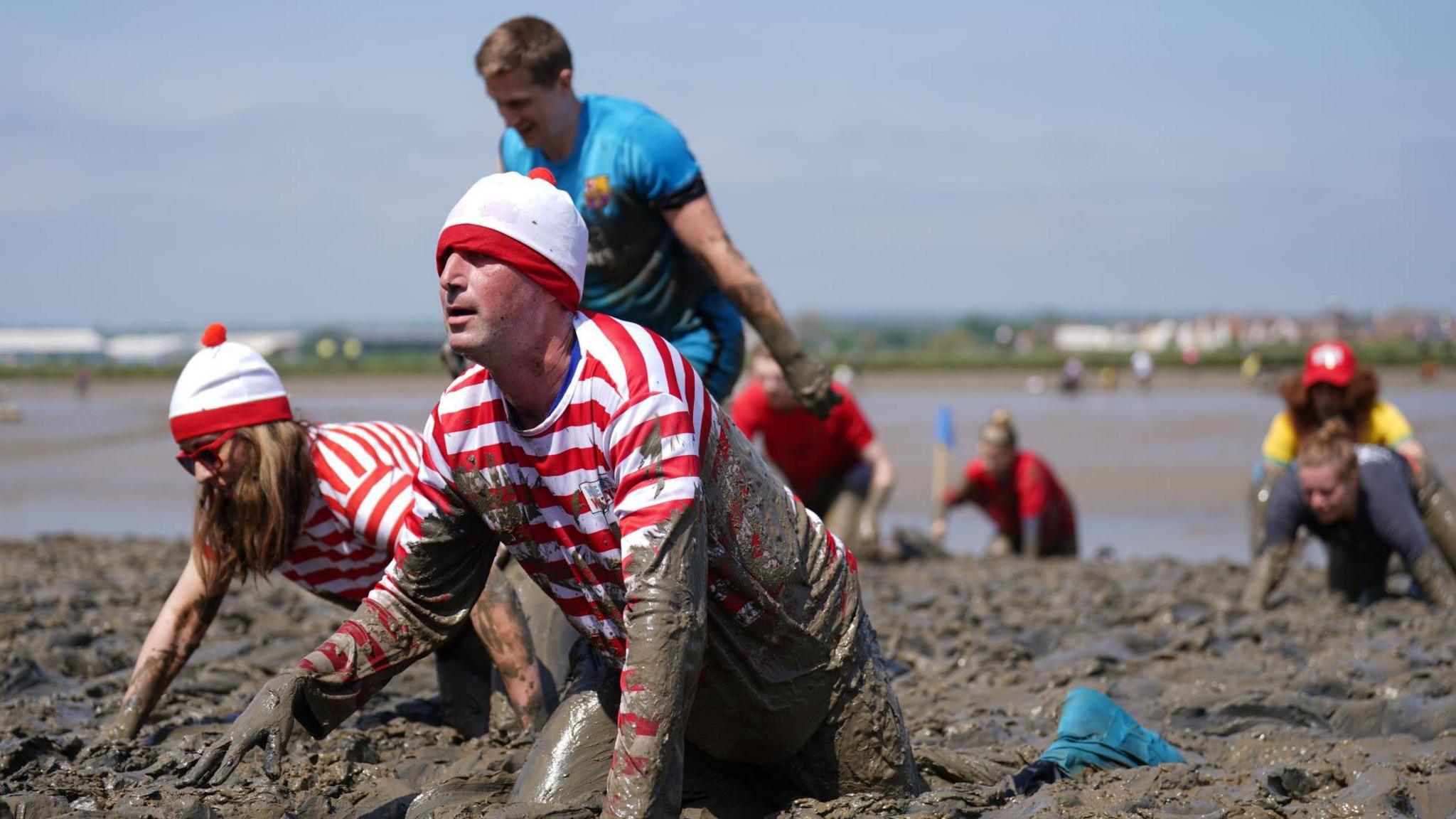 BBC Essex presenters Ben Fryer and Sonia Watson are crawling through mud at Hythe Quay for the Maldon Mud Race. They are dressed in Where's Wally outfits.