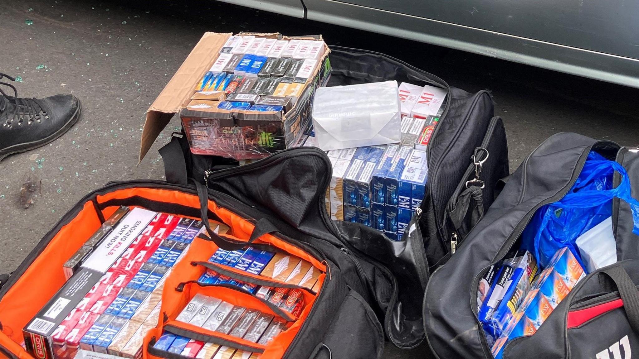 Holdall bags filled with packs of cigarettes and vapes.
