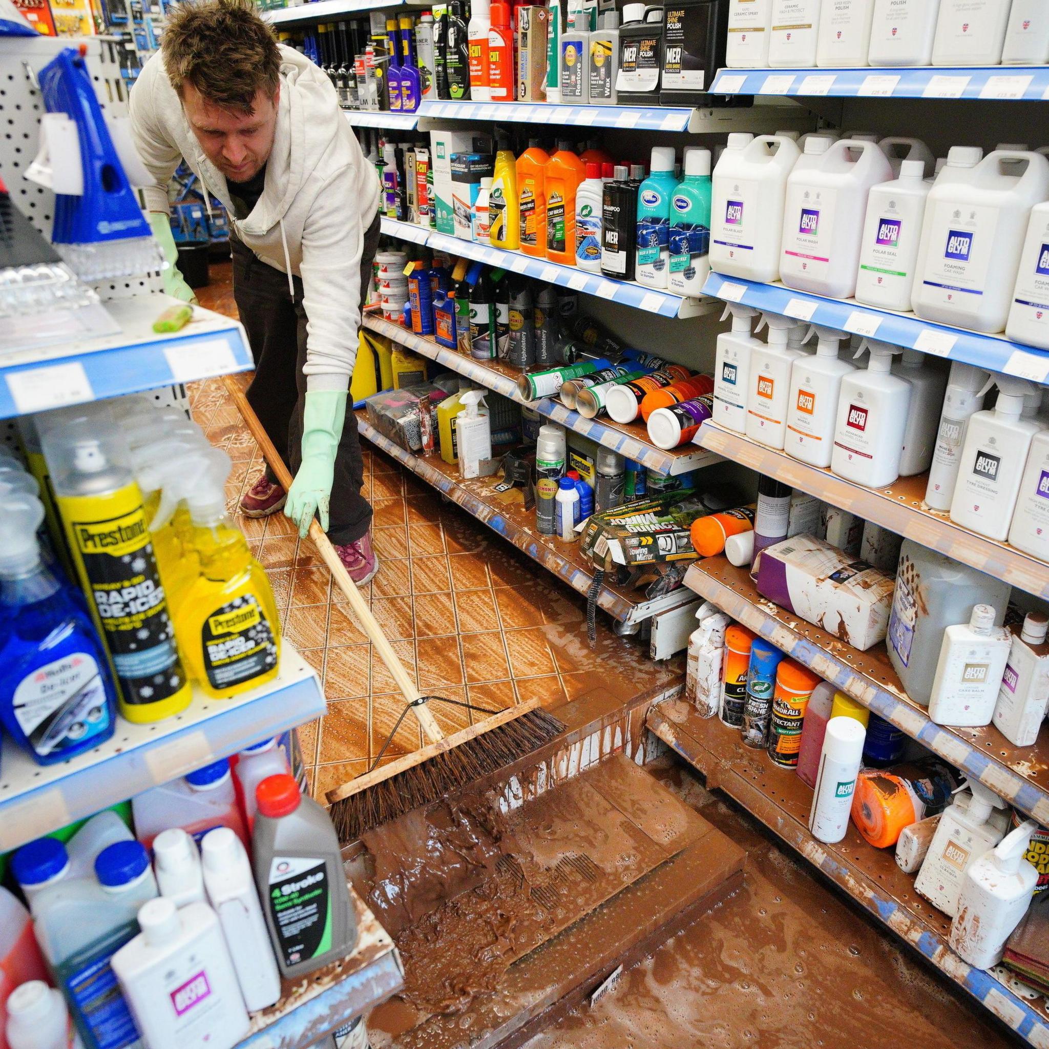 Man sweeps muddy water out of his shop