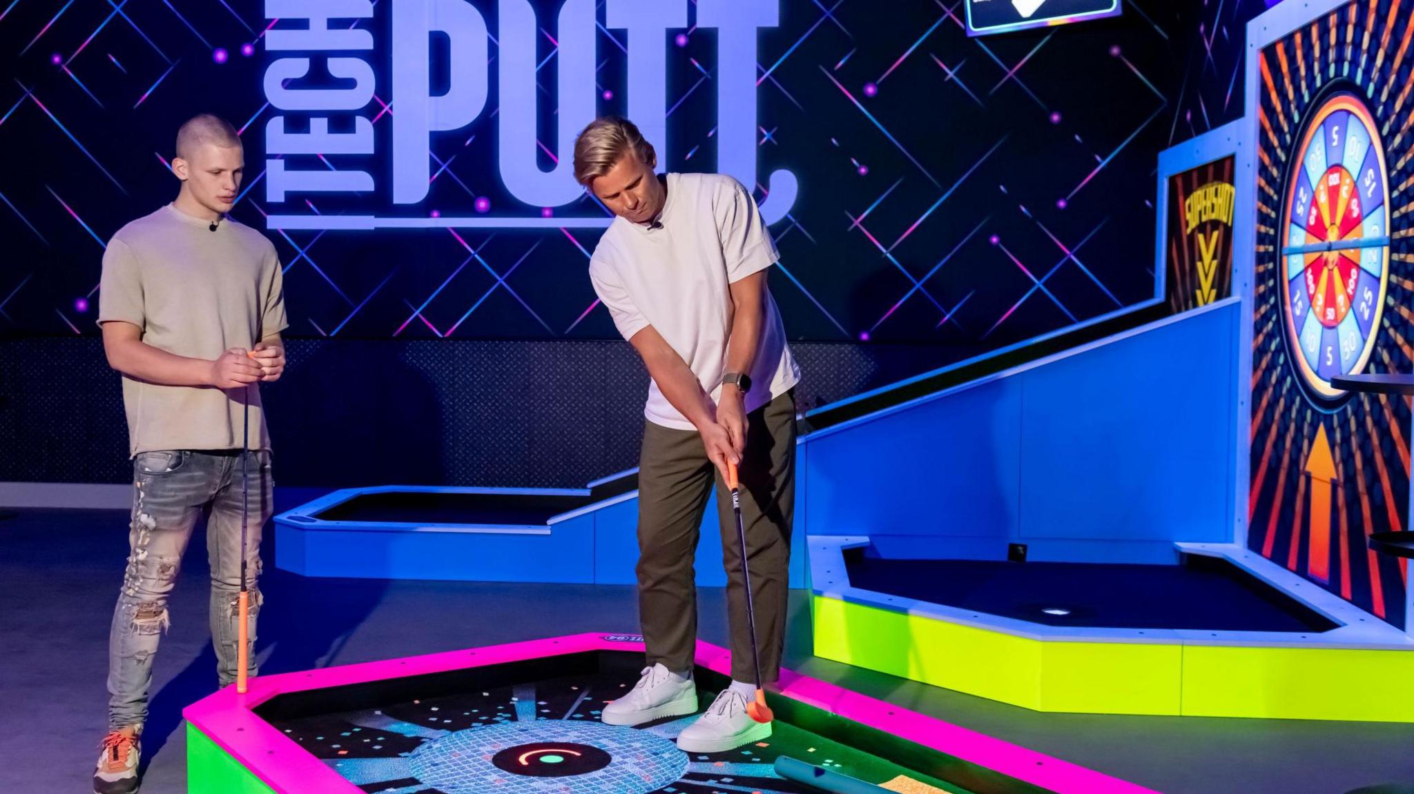 Two men play an indoor golf game 